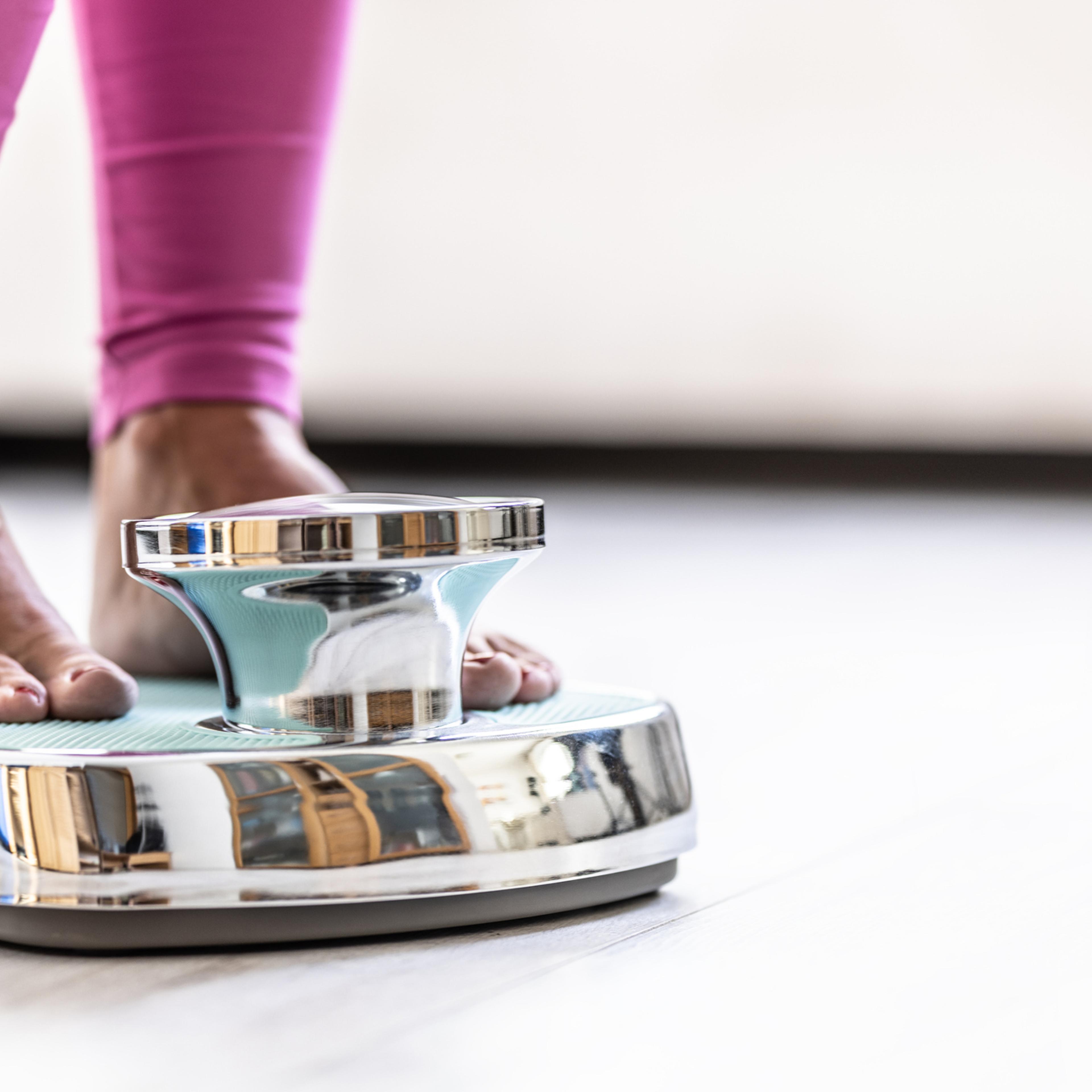 Woman standing on scale; close-up of legs.