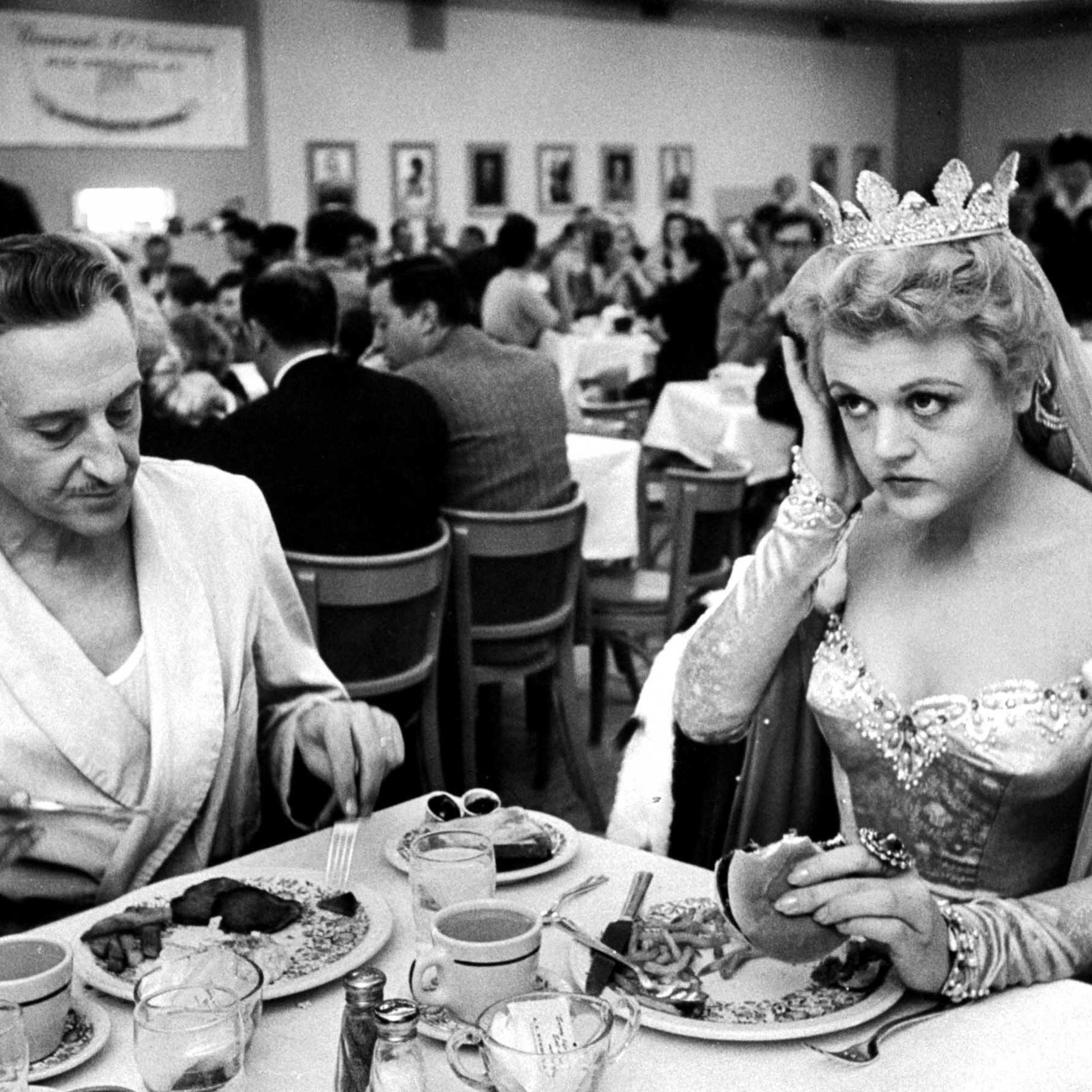 Angela Lansbury, in costume for her role in The Court Jester, eats lunch with Basil Rathbone in the Paramount Studio commissary, December 1954.