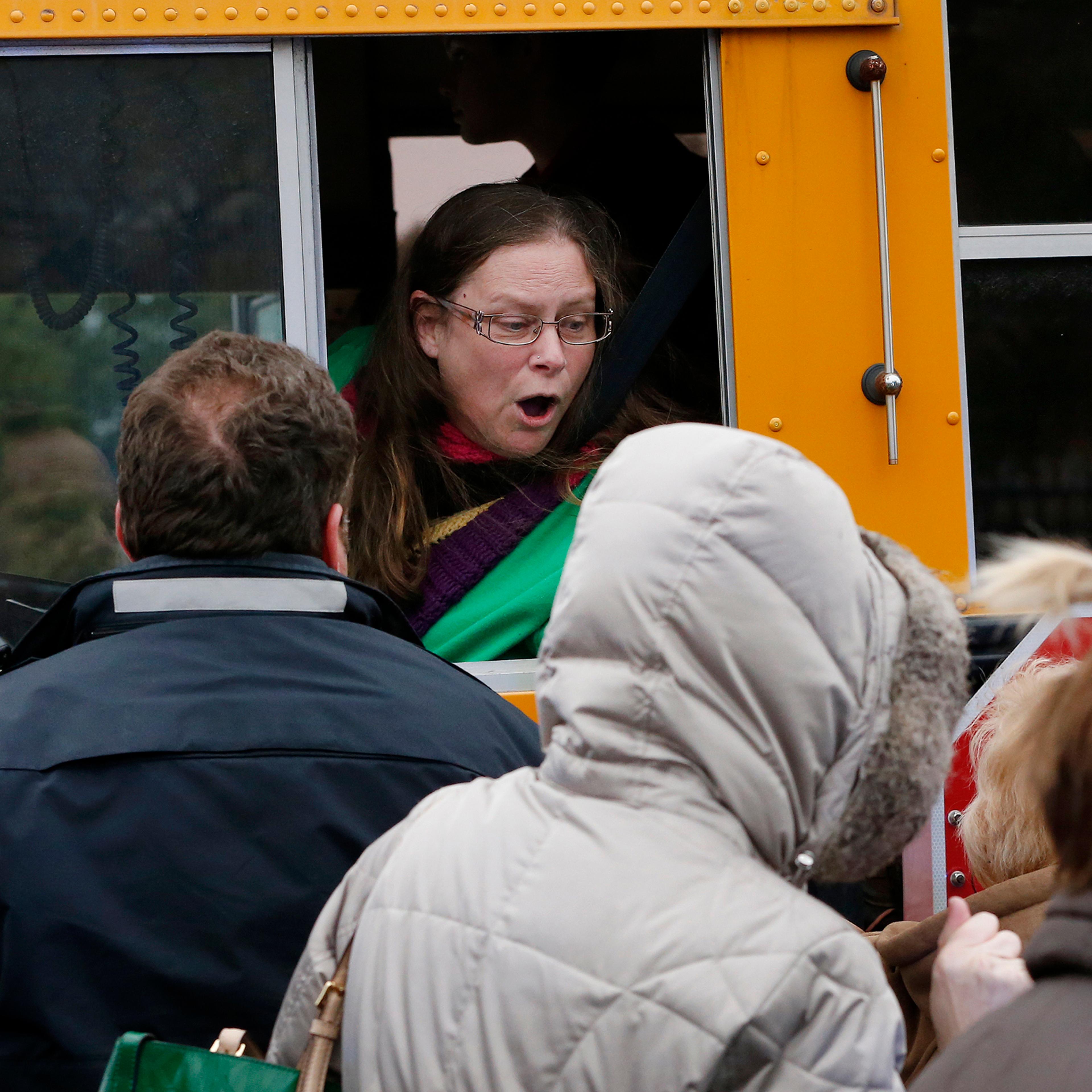A school bus driver yells to a parent that their child is safe after a bus accident at Amy Beverland Elementary School that left several students injured and one adult dead on school grounds on Jan. 26, 2016 in Indianapolis, Ind.