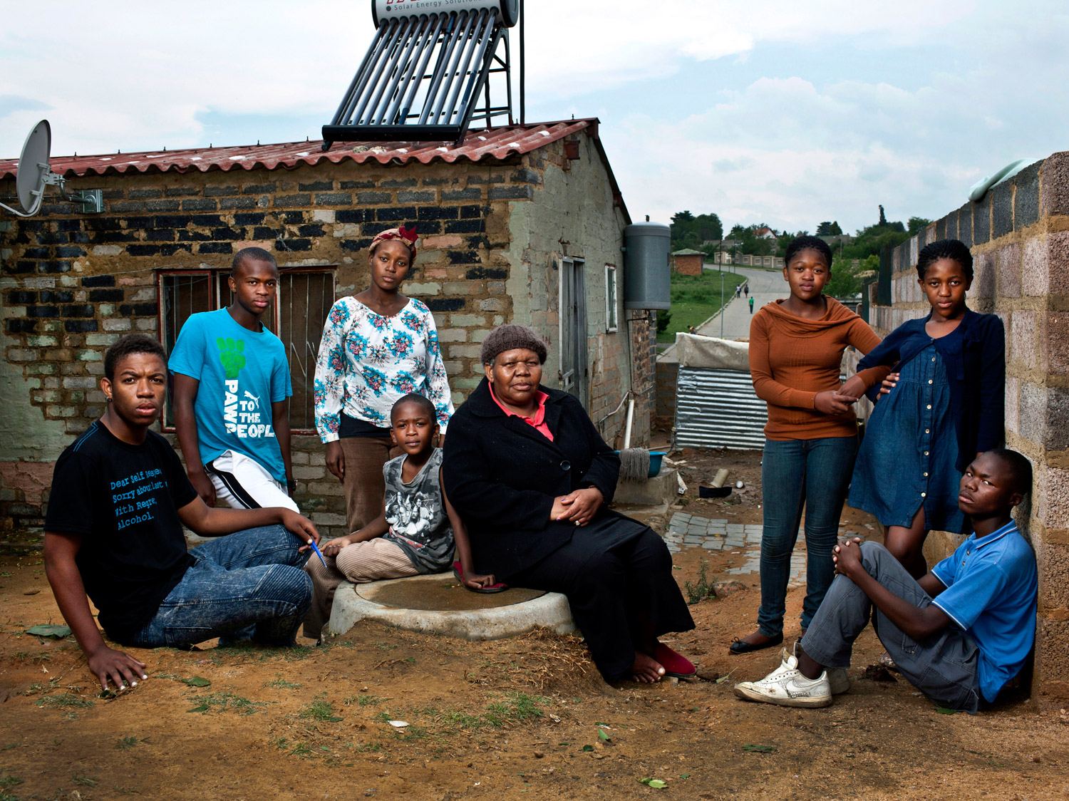 <b>Maria Mokoena, 62, with her seven orphan grandchildren. Alexandra township, Johannesburg, South Africa; October 2012.</b>
<br><br>
In 2003, Mokoena began taking care of grandchildren Ernest, now 21, and Lebusa, now 17, after her eldest daughter died of HIV/AIDS. This May, her second daughter also died of the disease, leaving her to raise five more grandchildren: Teddy, 8, Happy, 13, and Sharon, 15, Mbongeni, 17, and Lineo, 23. The grandchildren don't know how their mothers died. "They are too young to understand," Mokoena says. "This disease eats you from the inside until it is too late. I hope for a better life for my grandchildren. I want them to become accountants and lawyers.” 