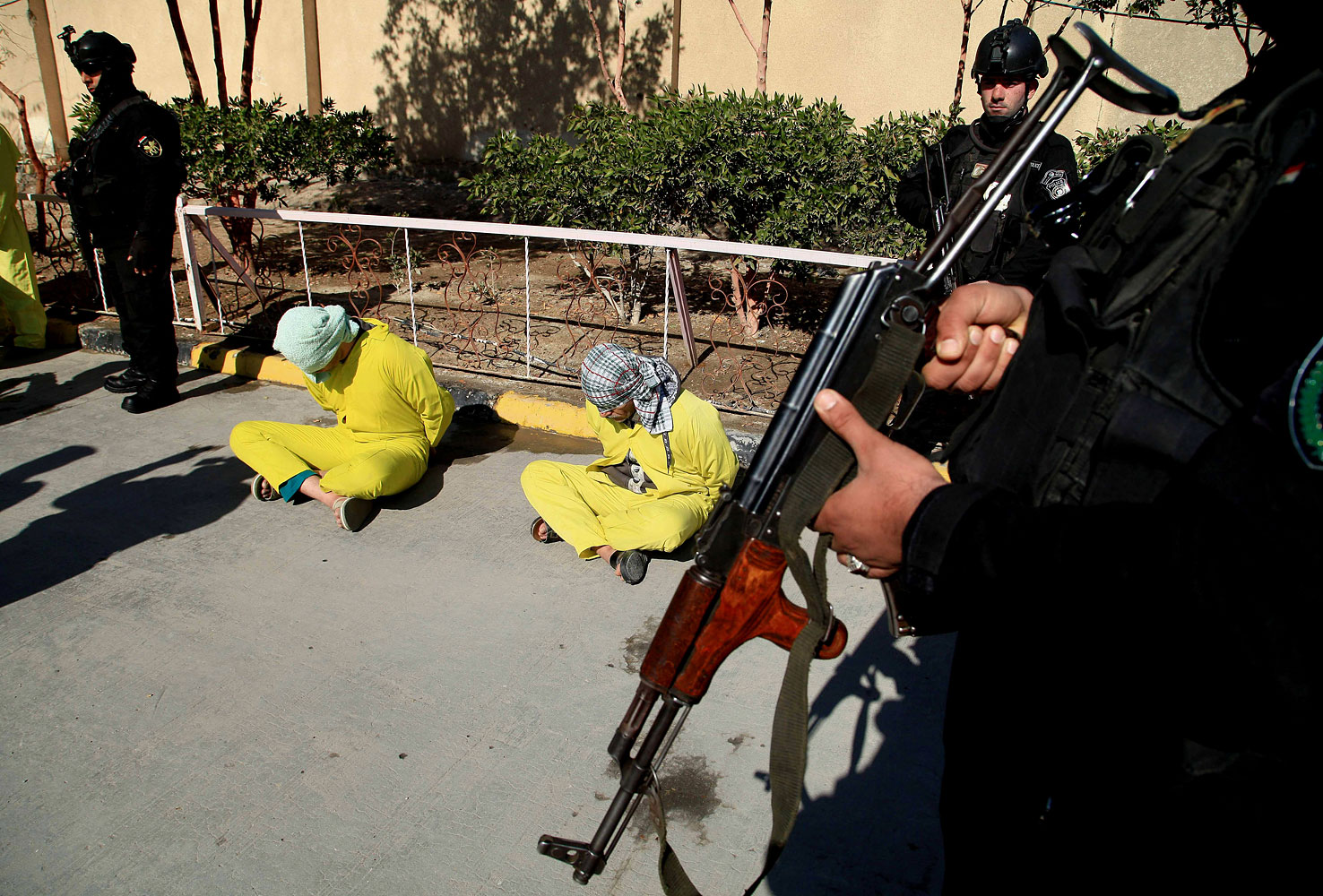 Members of Iraq's Special Weapons and Tactics Team stand guard as blindfolded suspected members of the al-Qaida-linked ISIS are displayed at the federal police headquarters in Basra, Feb 11, 2014.