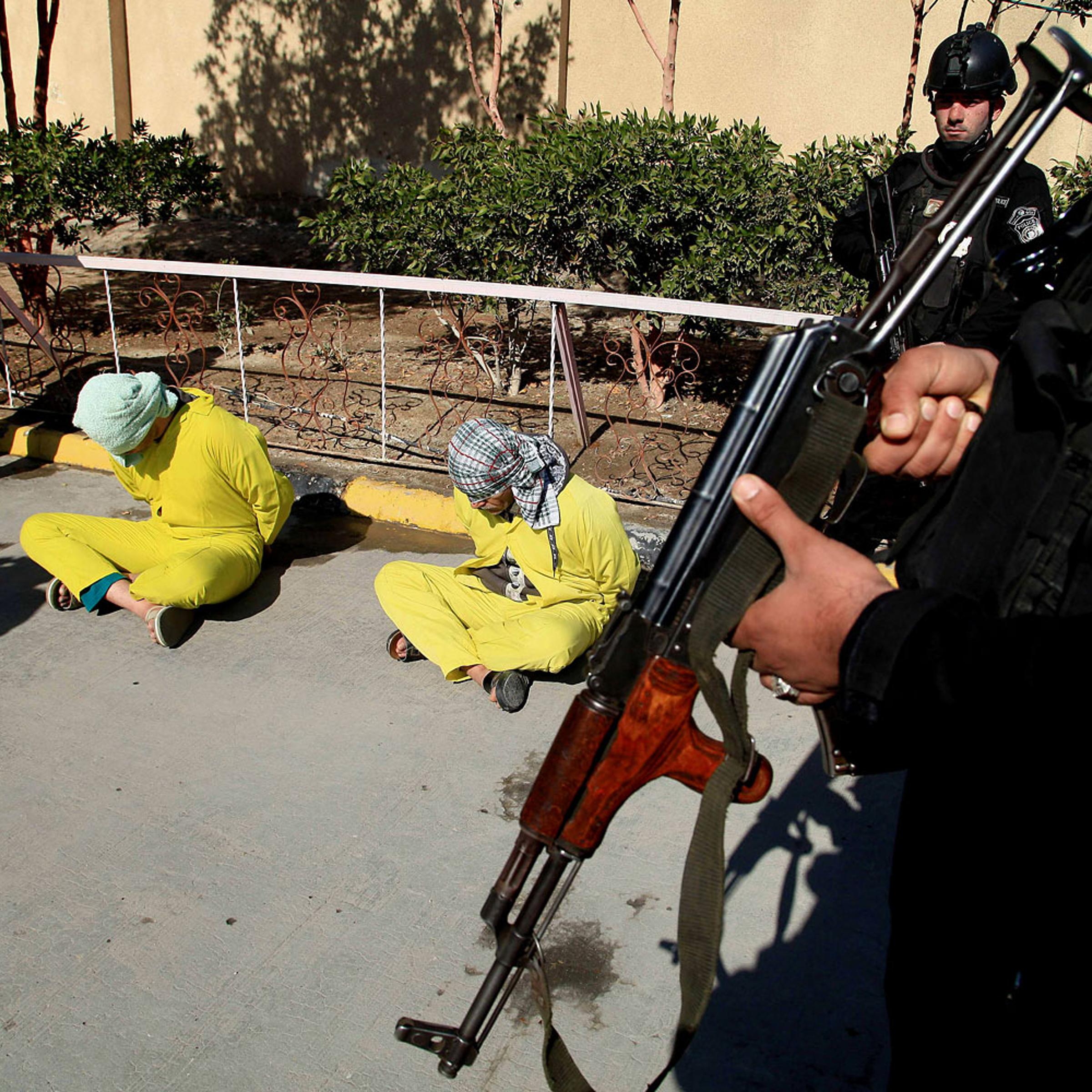 Members of Iraq's Special Weapons and Tactics Team stand guard as blindfolded suspected members of the al-Qaida-linked ISIS are displayed at the federal police headquarters in Basra, Feb 11, 2014.