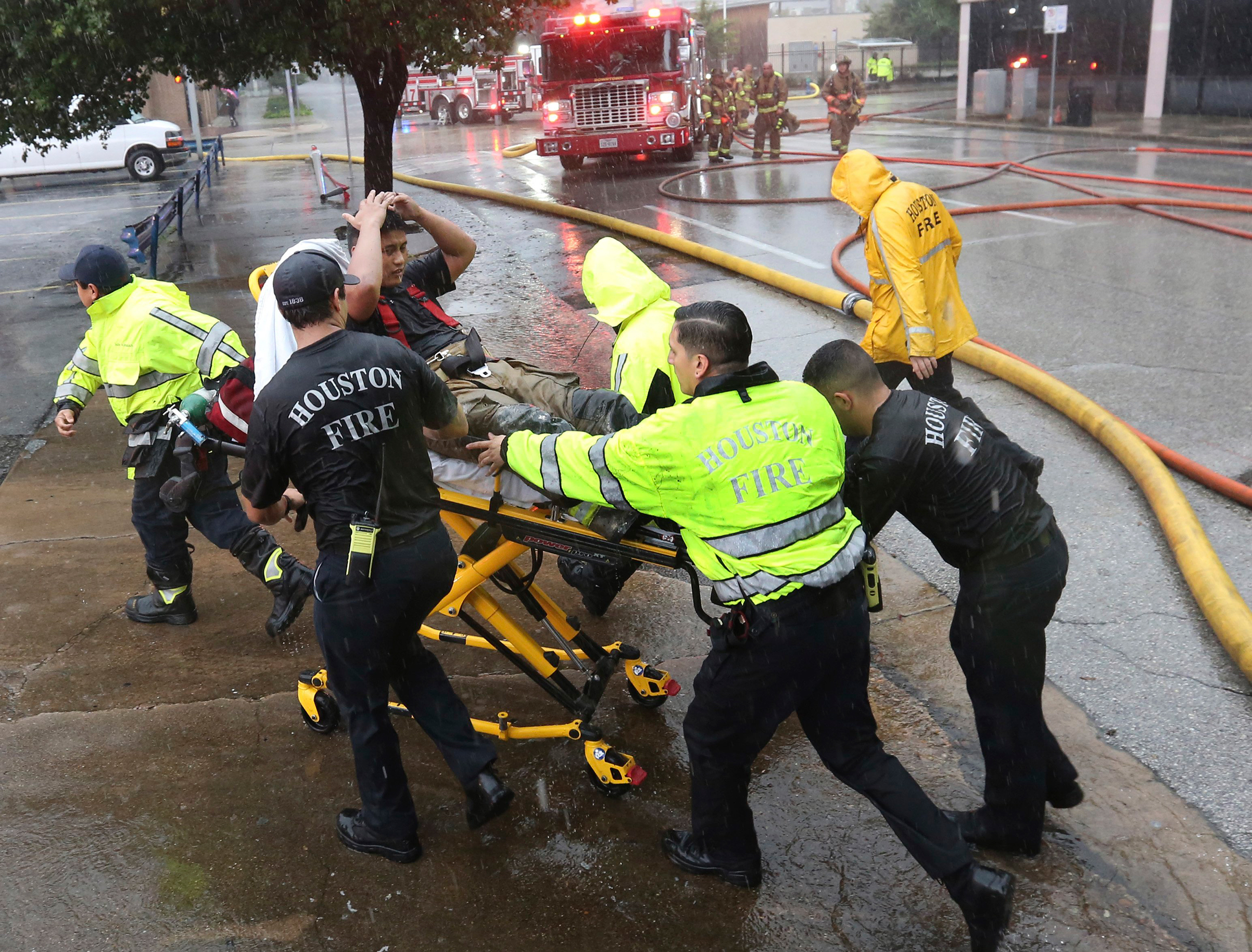 Rain from Tropical Storm Harvey falls as a firefighter is wheeled to a waiting ambulance after he became fatigued while fighting an office building fire in downtown in Houston, Aug. 28, 2017.