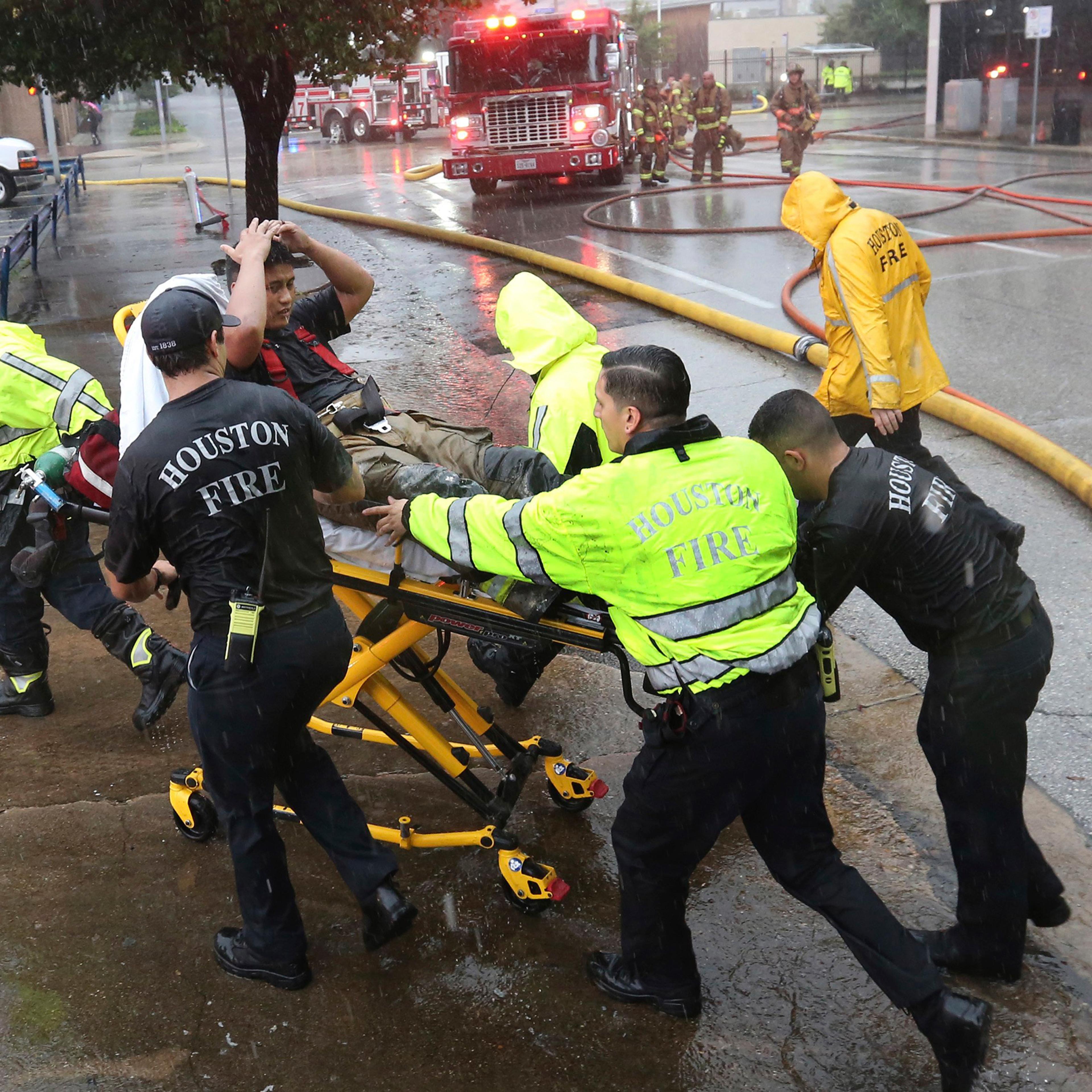 Rain from Tropical Storm Harvey falls as a firefighter is wheeled to a waiting ambulance after he became fatigued while fighting an office building fire in downtown in Houston, Aug. 28, 2017.