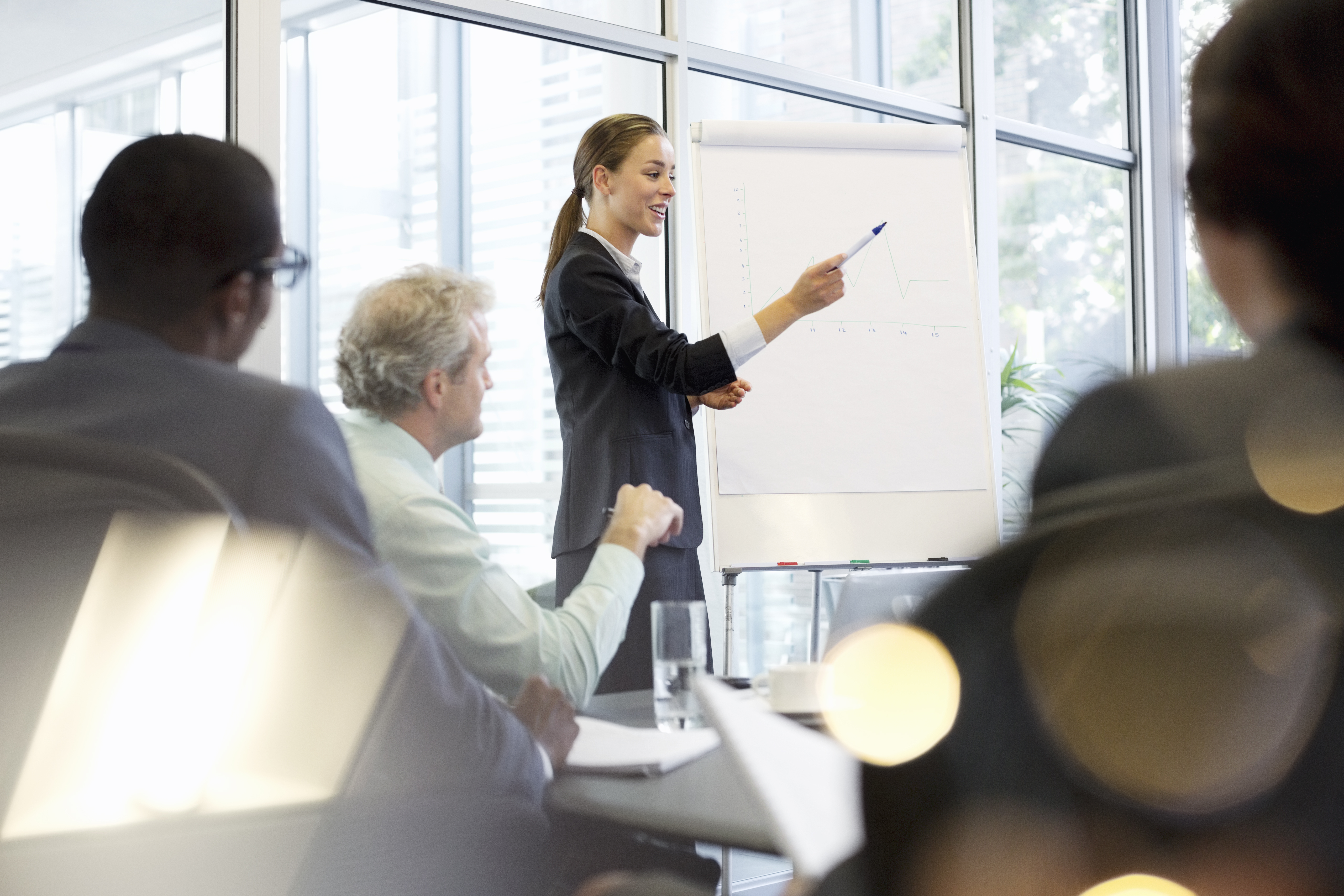 Businesswoman at flipchart leading meeting in conference room