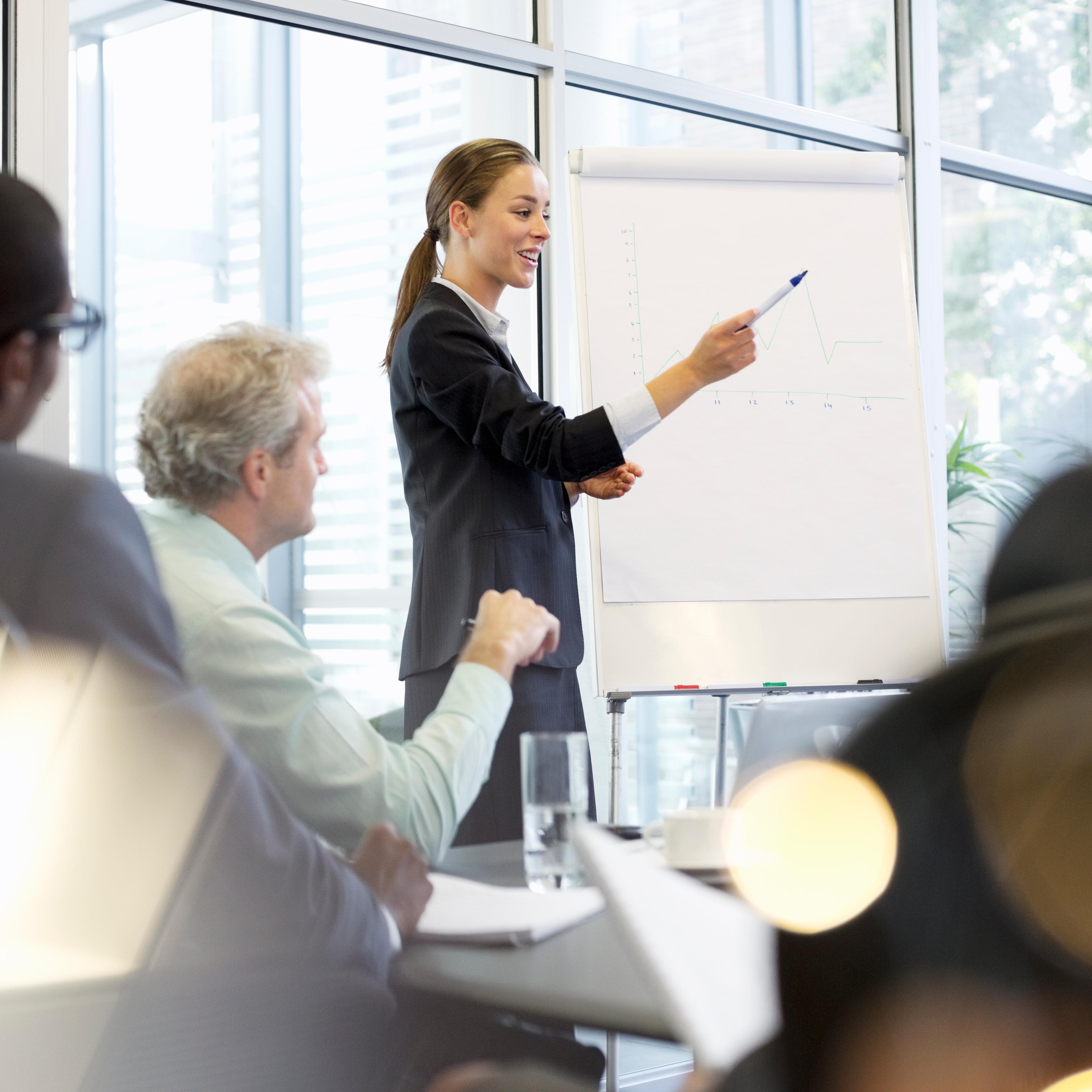 Businesswoman at flipchart leading meeting in conference room