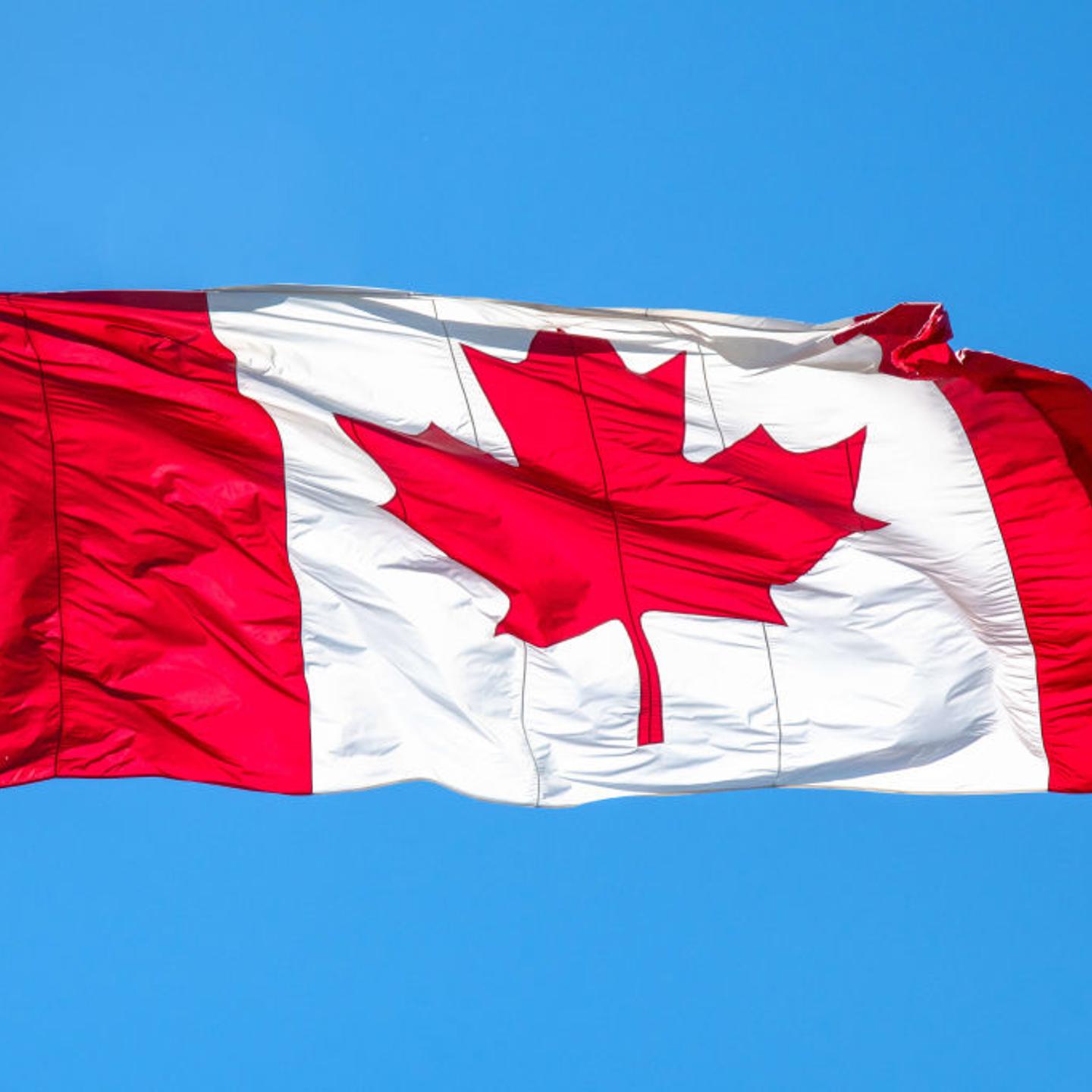 Flag of Canada or Canadian flag waving on blue clear sky