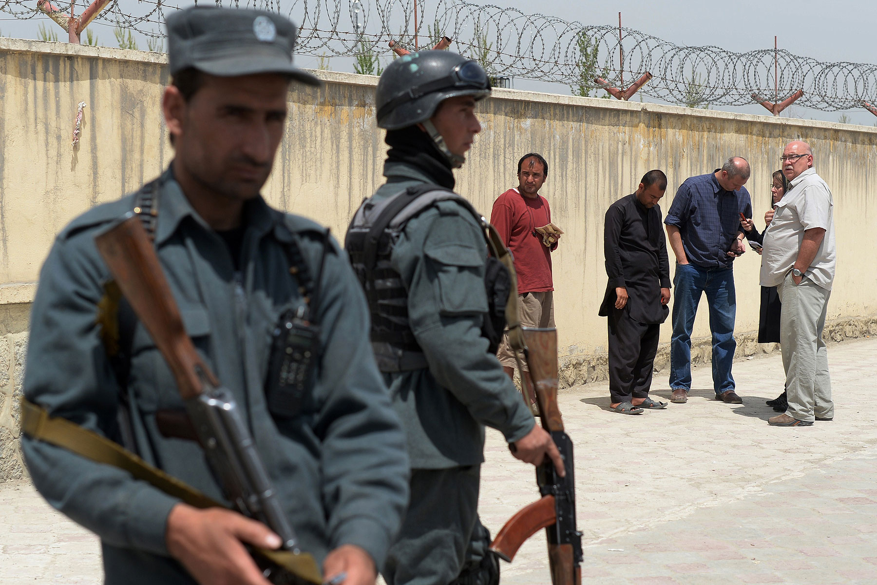 Afghan policemen keep watch as foreign nationals wait outside the Cure hospital in Kabul on April 24, 2014