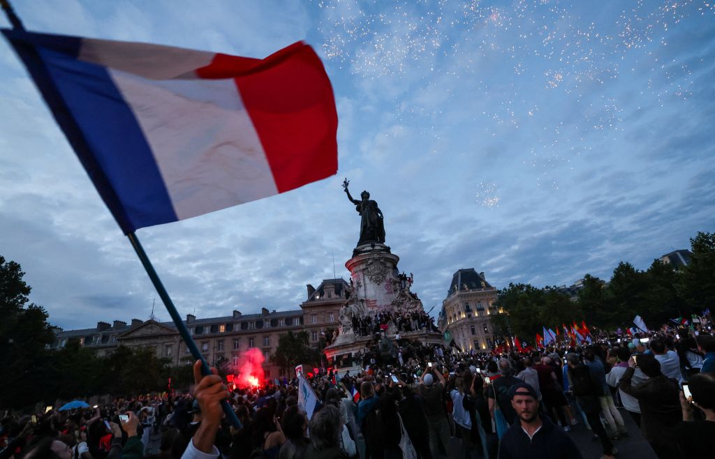 A participant waves a French national tricolor during an election night rally following the first results of the second round of France's legislative election at Place de la Republique in Paris on July 7, 2024.