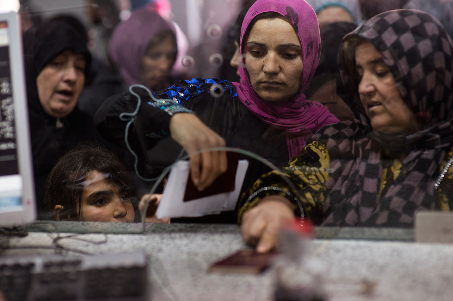 Syrians line up with their passports to enter Lebanon at immigration at the official border crossing in Masnaa, Lebanon, March 13, 2014.
