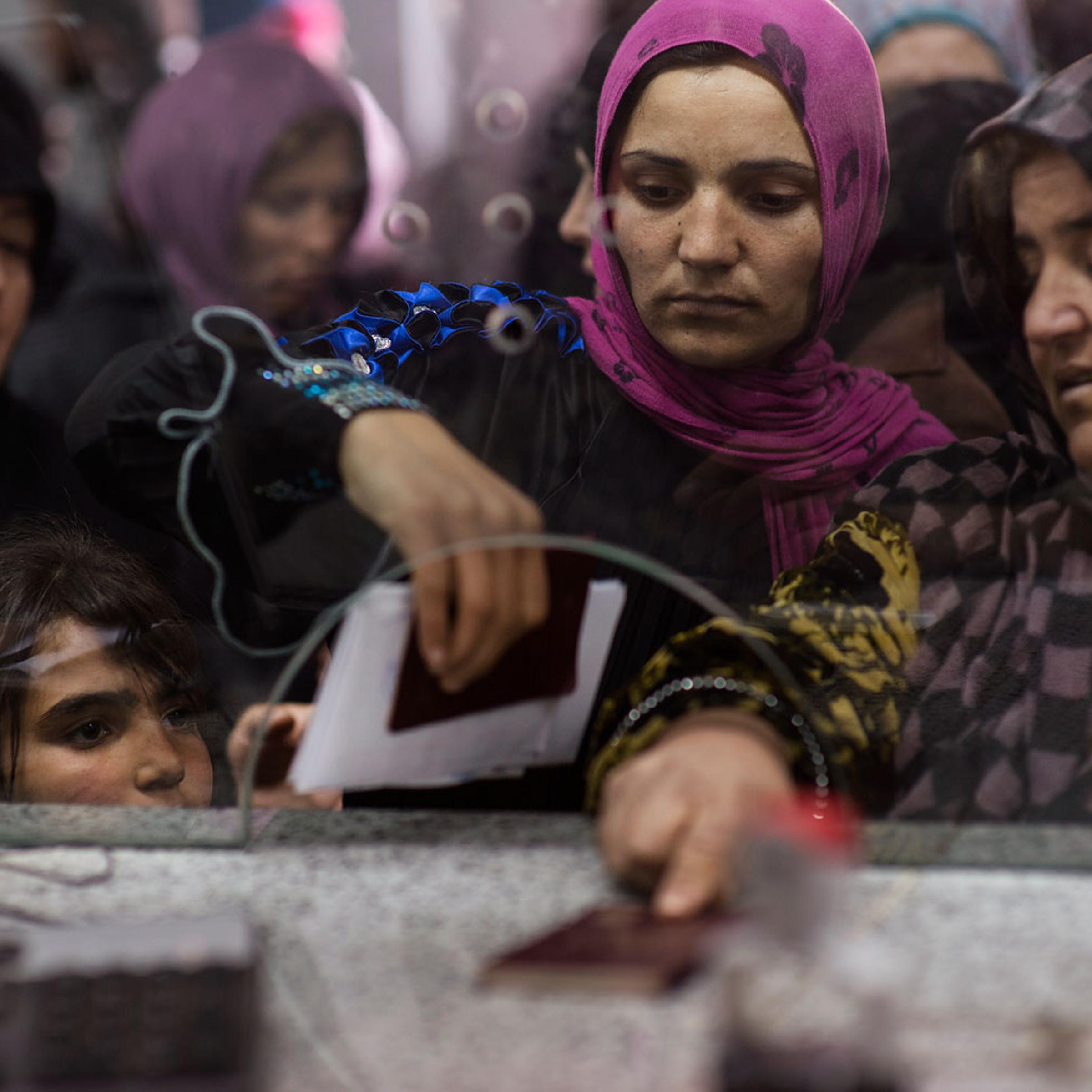 Syrians line up with their passports to enter Lebanon at immigration at the official border crossing in Masnaa, Lebanon, March 13, 2014.