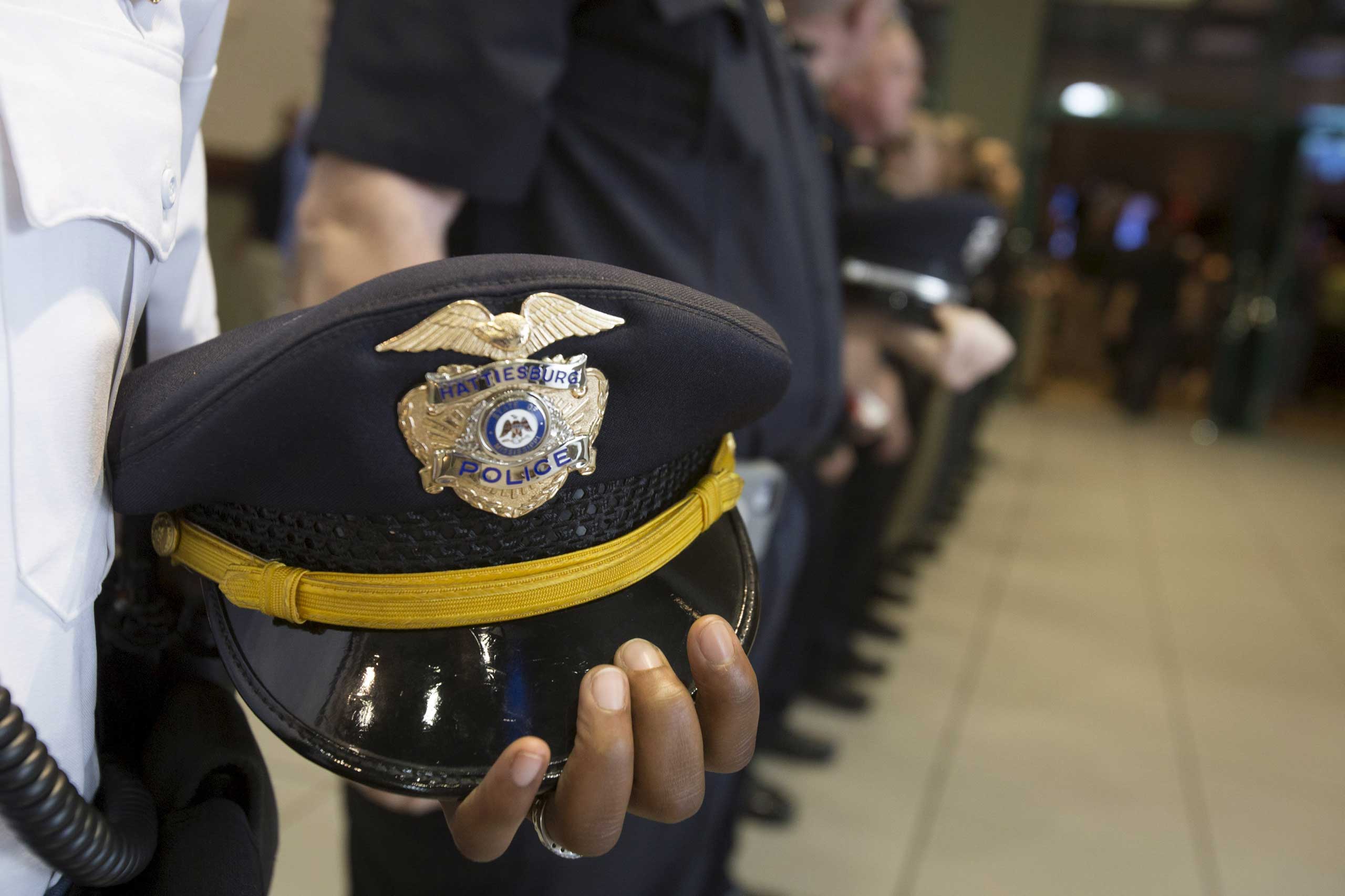 Policemen hold their hats at their side during a vigil service for two fellow officers killed during a traffic stop, in Hattiesburg