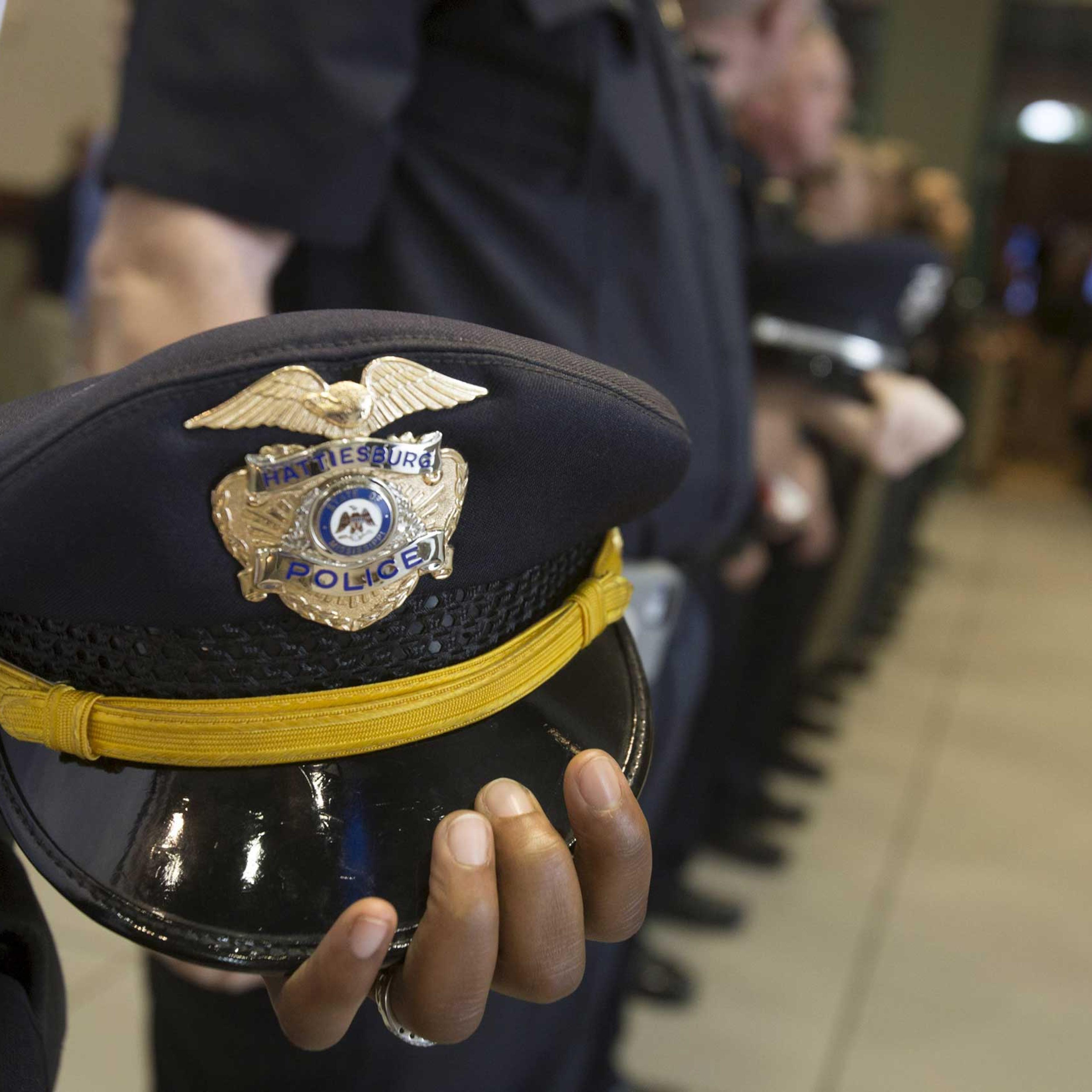 Policemen hold their hats at their side during a vigil service for two fellow officers killed during a traffic stop, in Hattiesburg