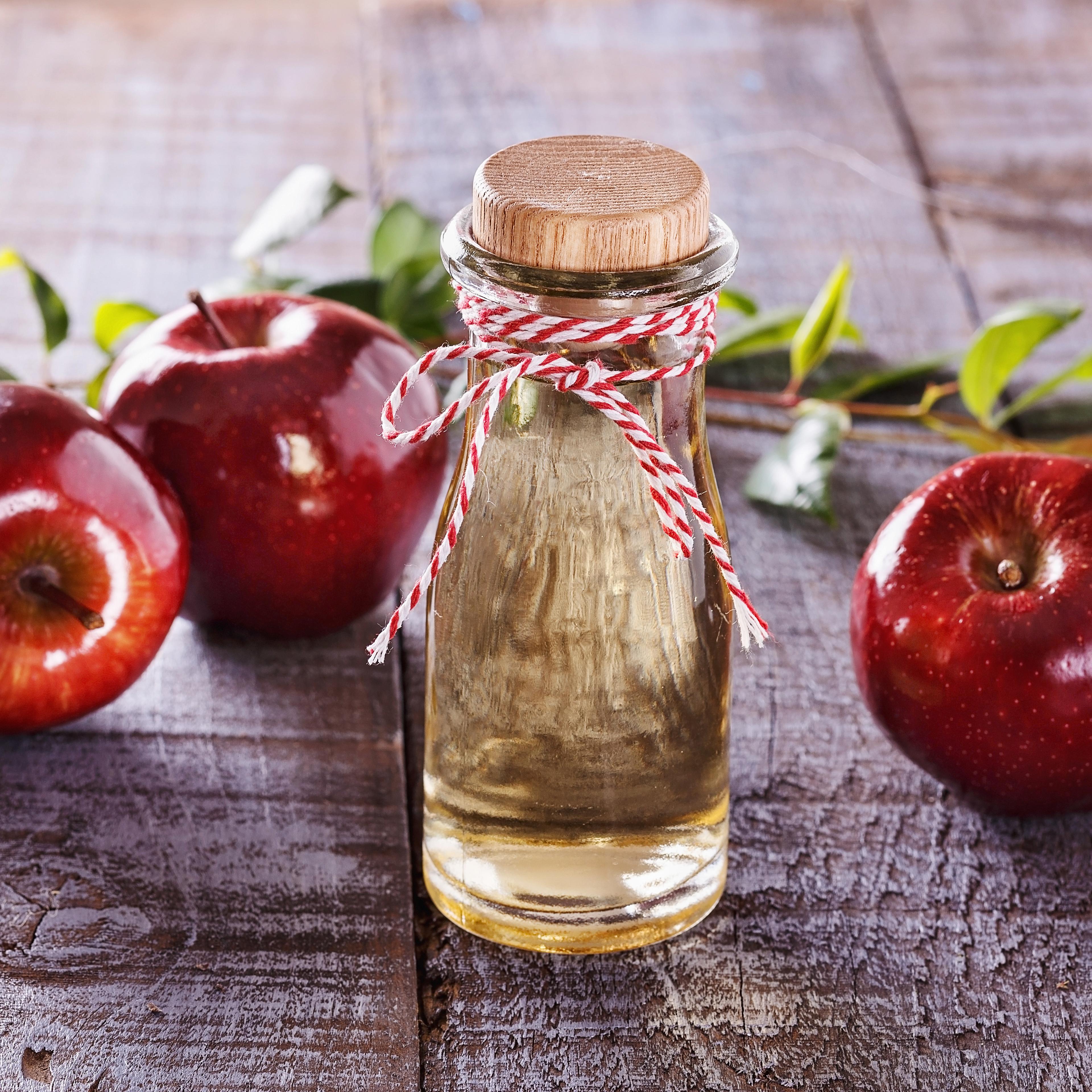 Apple cider vinegar over rustic wooden background