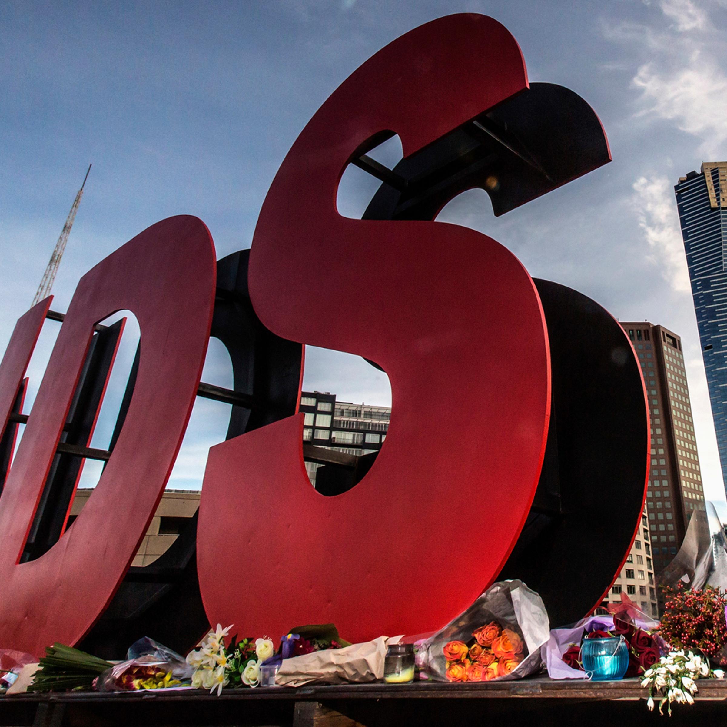 Flowers are laid as tributes to those killed in the Malaysia Airlines flight MH17, at the base of large sign for 20th International AIDS Conference in Melbourne