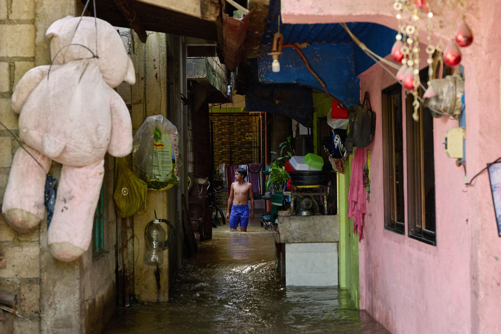 A man wades past flooded houses due to a swollen river caused by heavy rains and induced by Super Typhoon Man-yi in Tuguegarao City, Cagayan province, Philippines on Nov. 19, 2024.