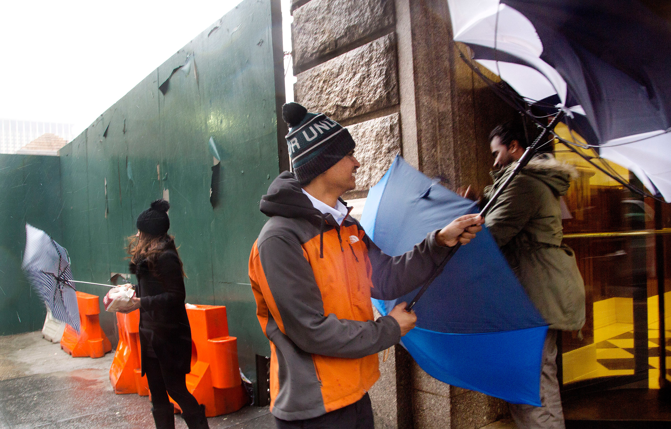 Three people struggle with their umbrellas against high winds in New York, Feb. 16, 2016.