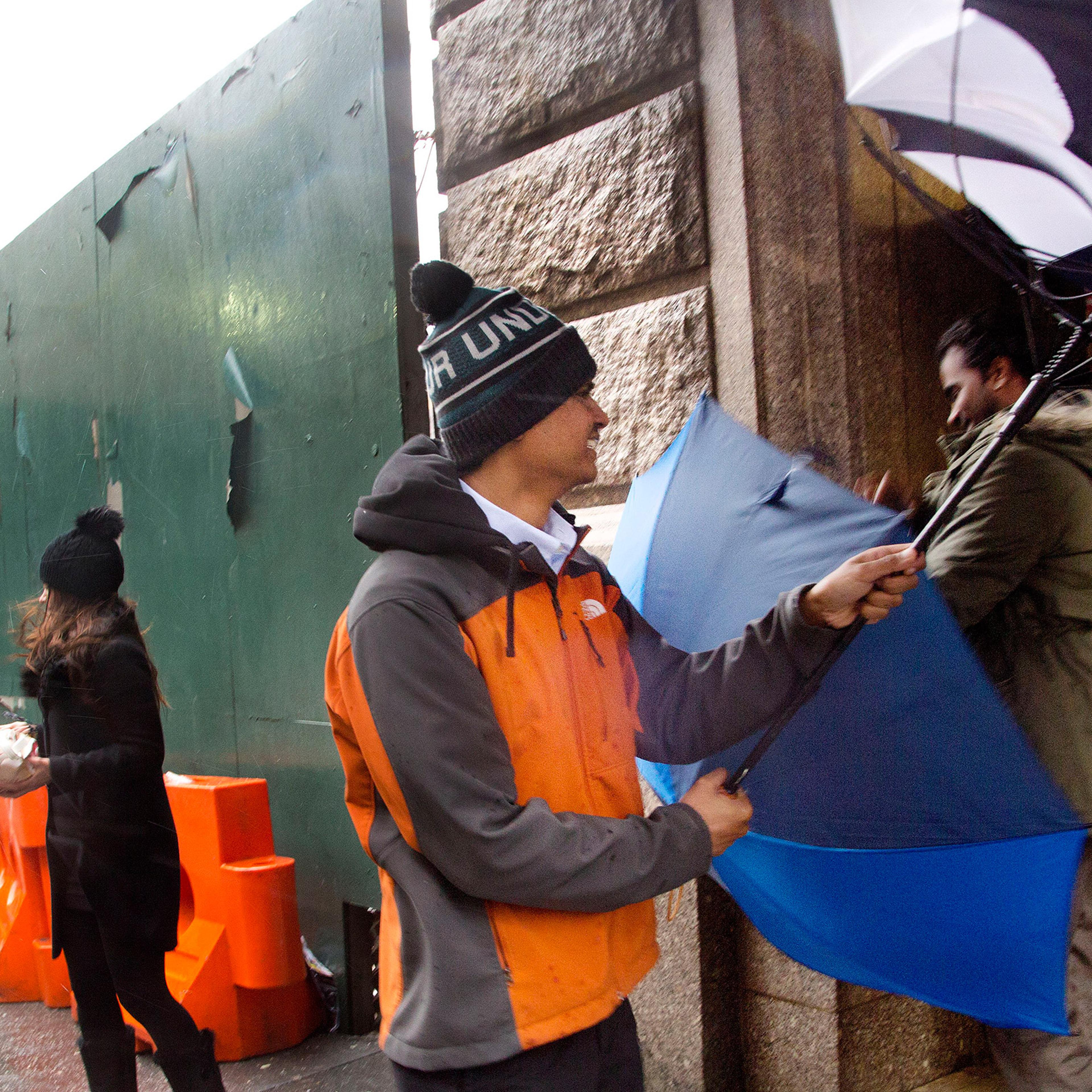 Three people struggle with their umbrellas against high winds in New York, Feb. 16, 2016.