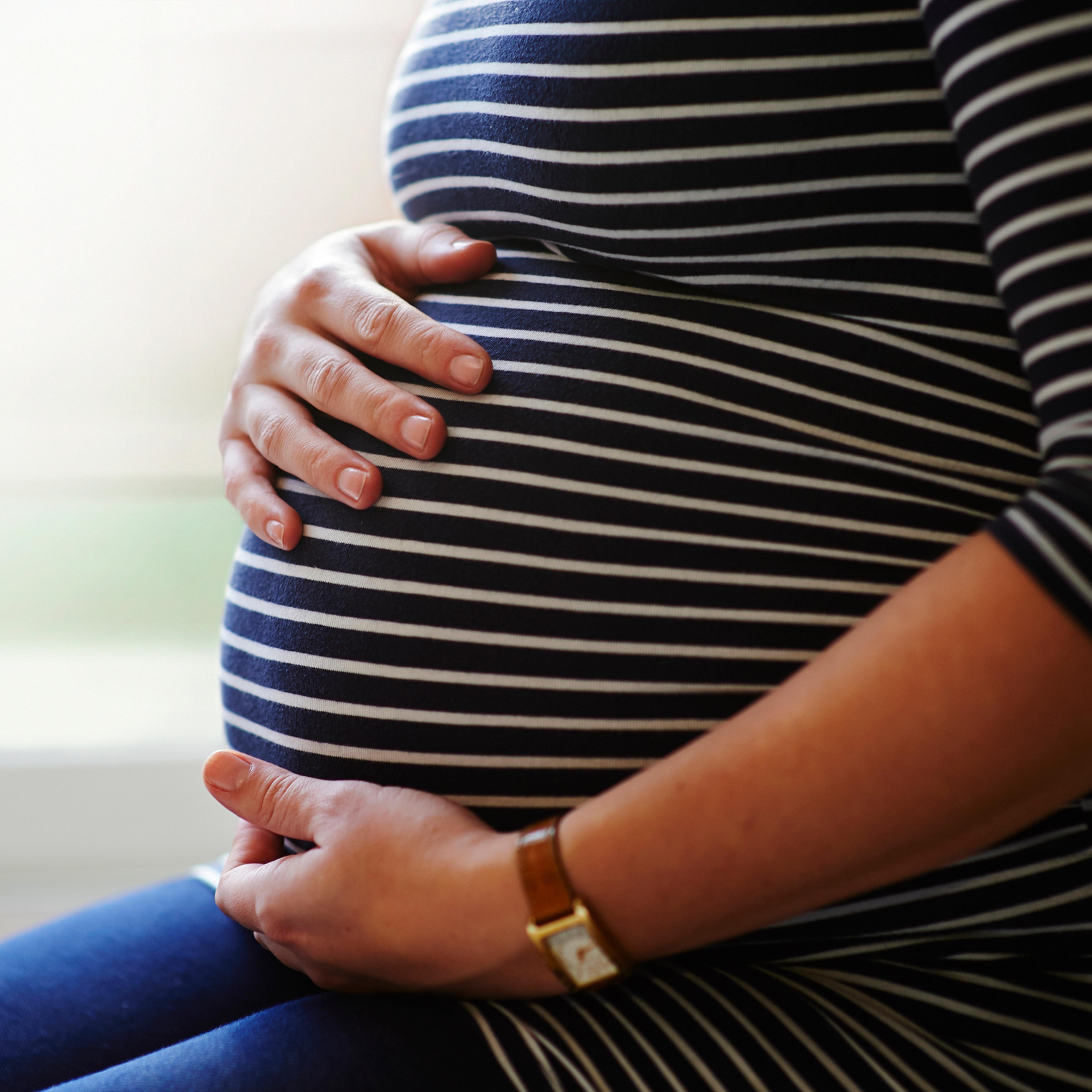 Heavily pregnant woman holding her bump