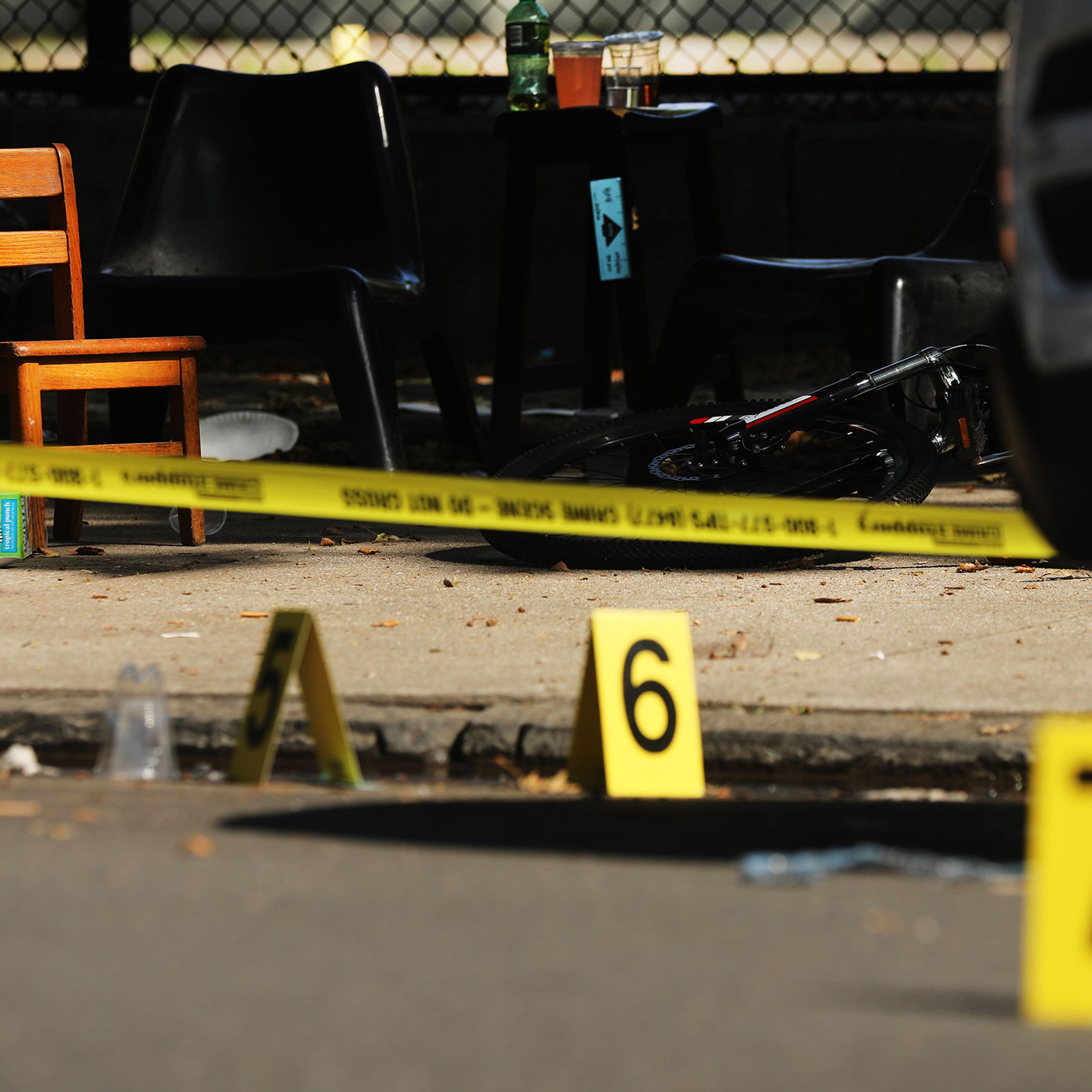 Police ballistic markers stand beside a child's chair and bicycle at a crime scene in Brooklyn where a one year old child was shot and killed on July 13, 2020 in New York City