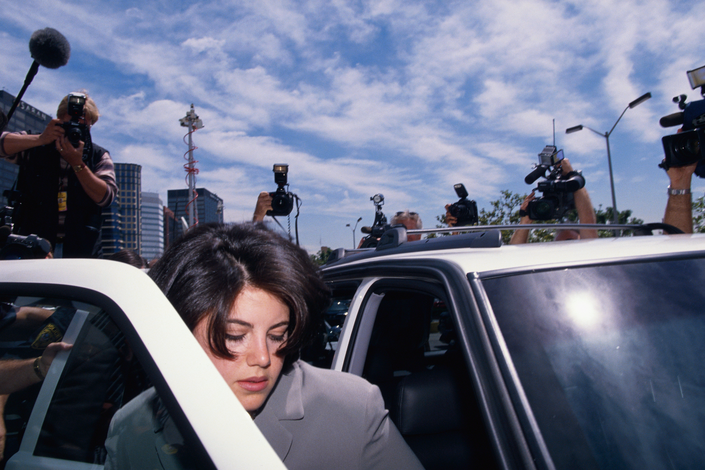 Monica Lewinsky is surrounded by photographers as she gets into car to go to the FBI Headquarters.