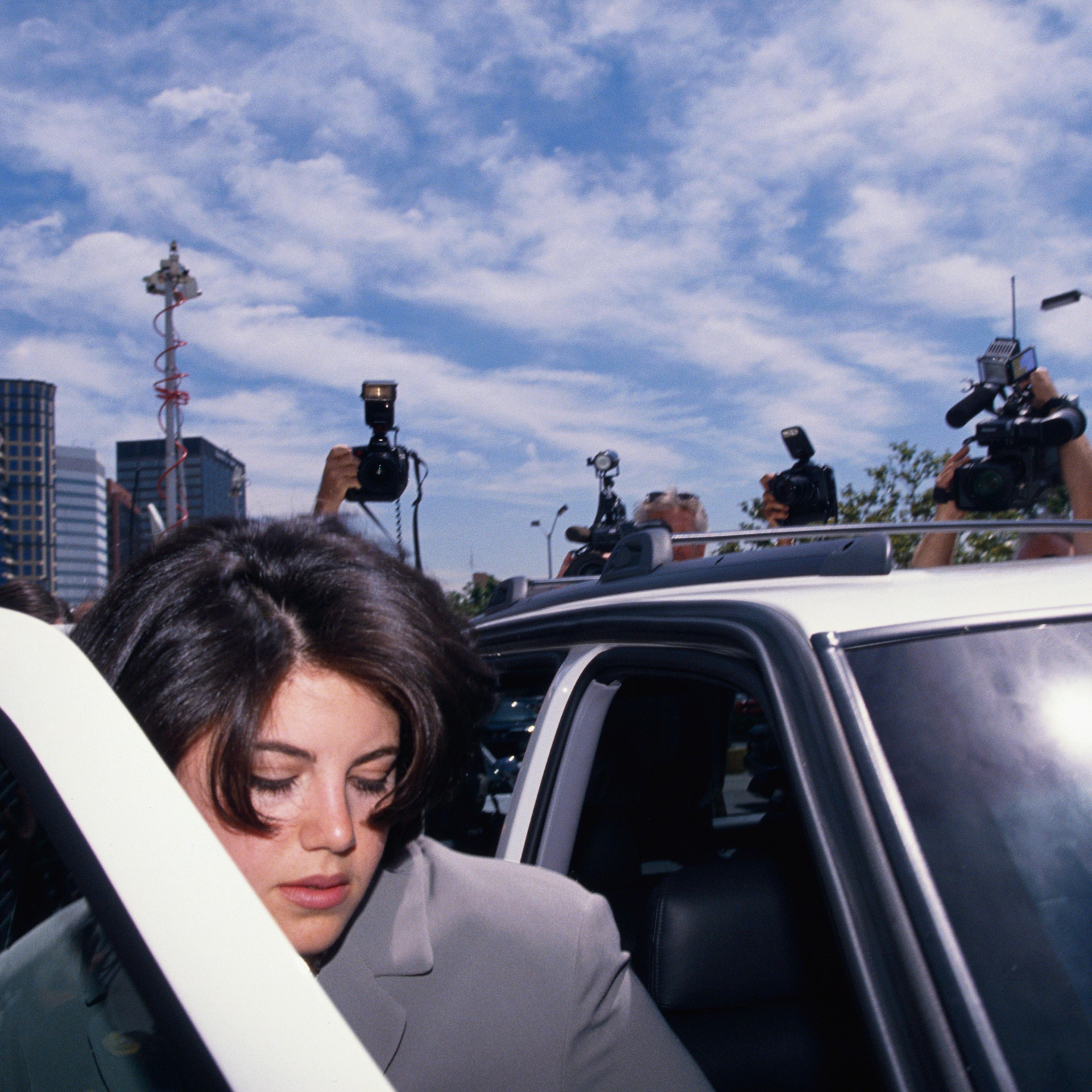 Monica Lewinsky is surrounded by photographers as she gets into car to go to the FBI Headquarters.