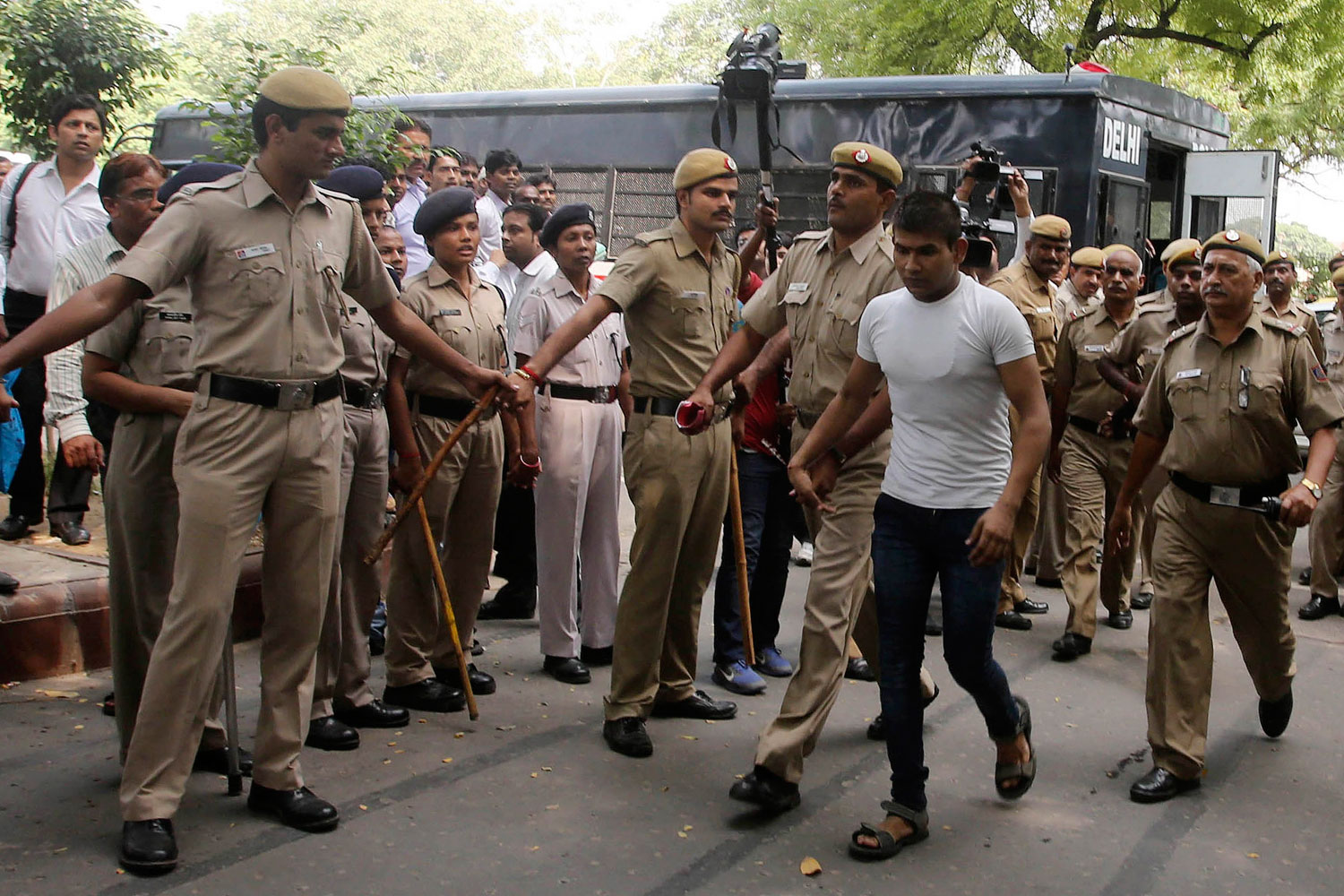 Vinay Sharma (wearing white T-shirt), one of the four men who were sentenced to death for fatally raping a young woman on a bus last December, is escorted by police outside a court in New Delhi Sept. 24, 2013.