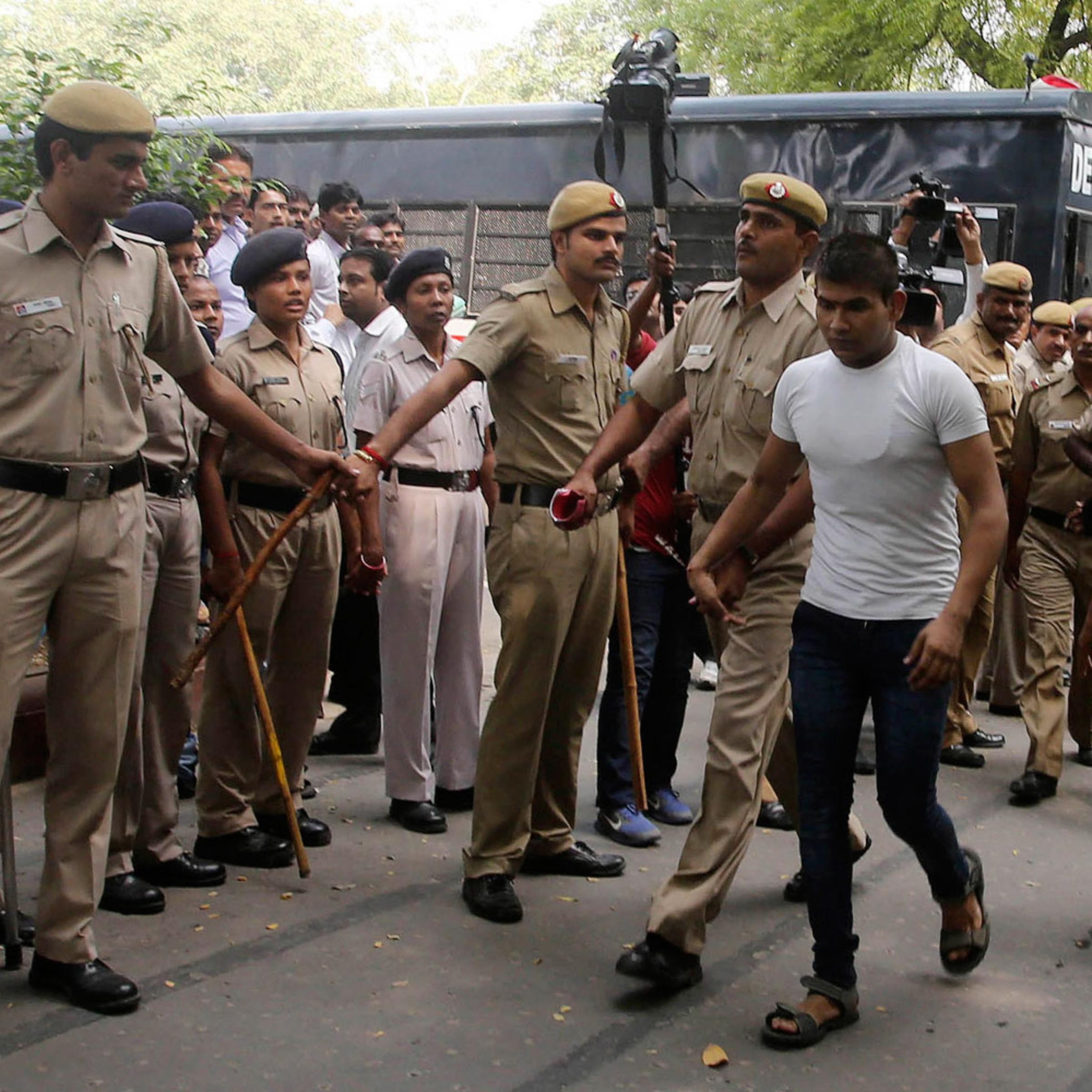 Vinay Sharma (wearing white T-shirt), one of the four men who were sentenced to death for fatally raping a young woman on a bus last December, is escorted by police outside a court in New Delhi Sept. 24, 2013.