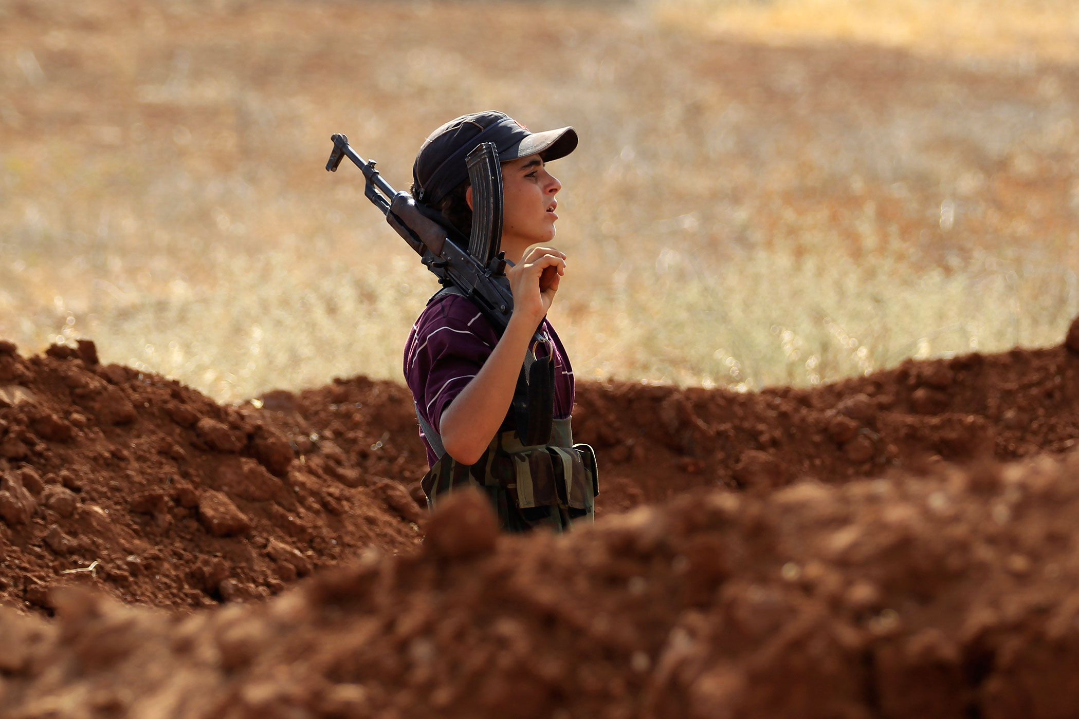 A Free Syrian Army fighter carries his weapon on one of the frontlines of Wadi Al-Dayf camp in the southern Idlib countryside