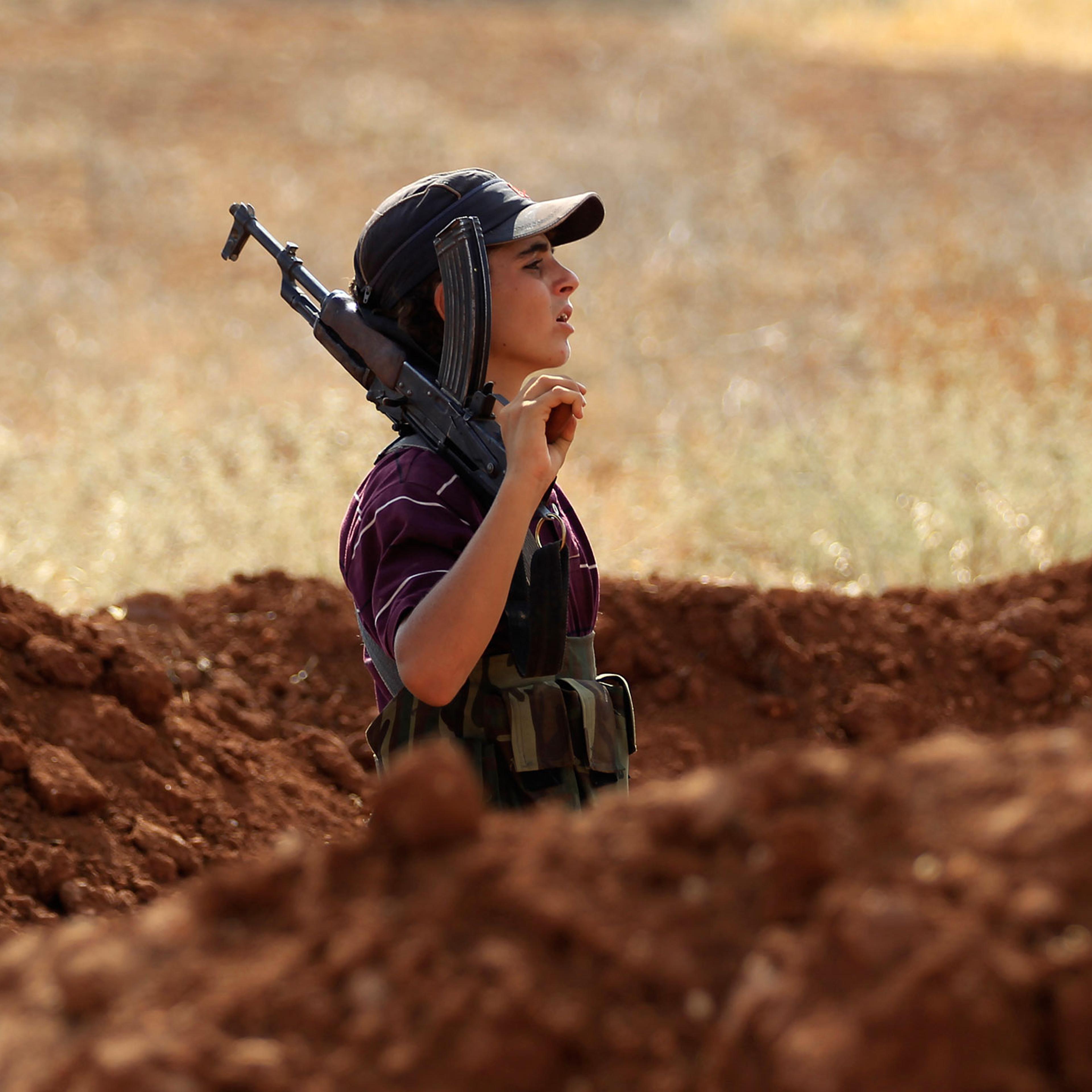 A Free Syrian Army fighter carries his weapon on one of the frontlines of Wadi Al-Dayf camp in the southern Idlib countryside