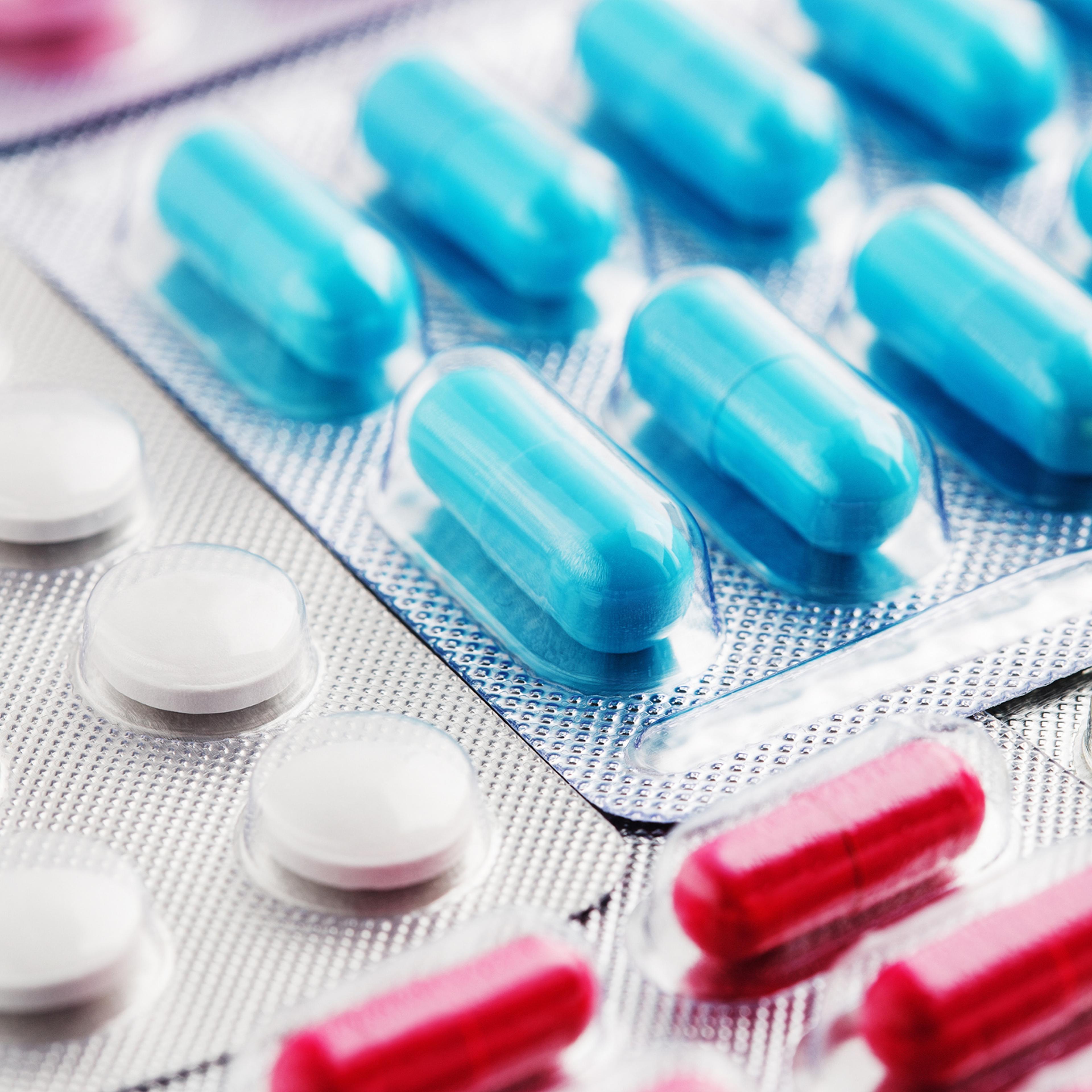 Heap of medical pills in white, blue and other colors. Pills in plastic package. Concept of healthcare and medicine.