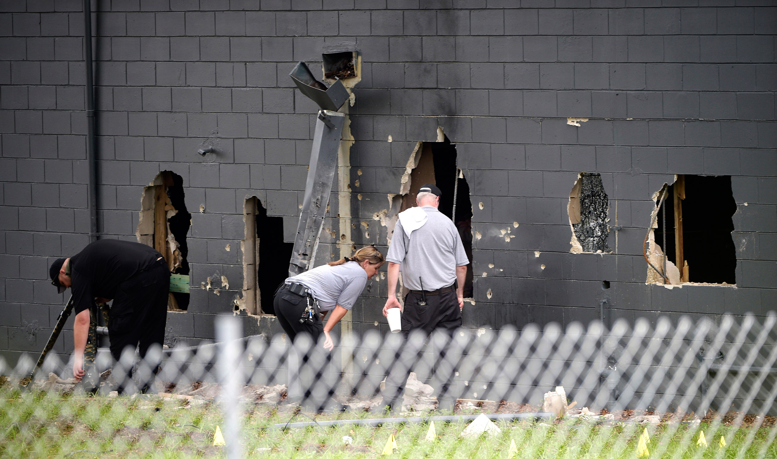 Police officials investigate the back of the Pulse nightclub after a shooting involving multiple fatalities at the nightclub in Orlando, Fla., Sunday, June 12, 2016. (AP Photo/Phelan M. Ebenhack)