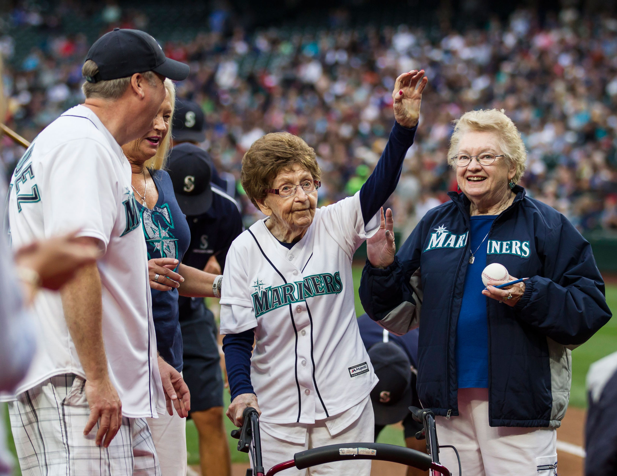 108-year-old Evelyn Jones, center, of Woodinville, Wash., waves to the crowd after throwing out the ceremonial first pitch on her birthday before a baseball game between the Seattle Mariners and the Los Angeles Angels, Saturday, July 11, 2015, in Seattle