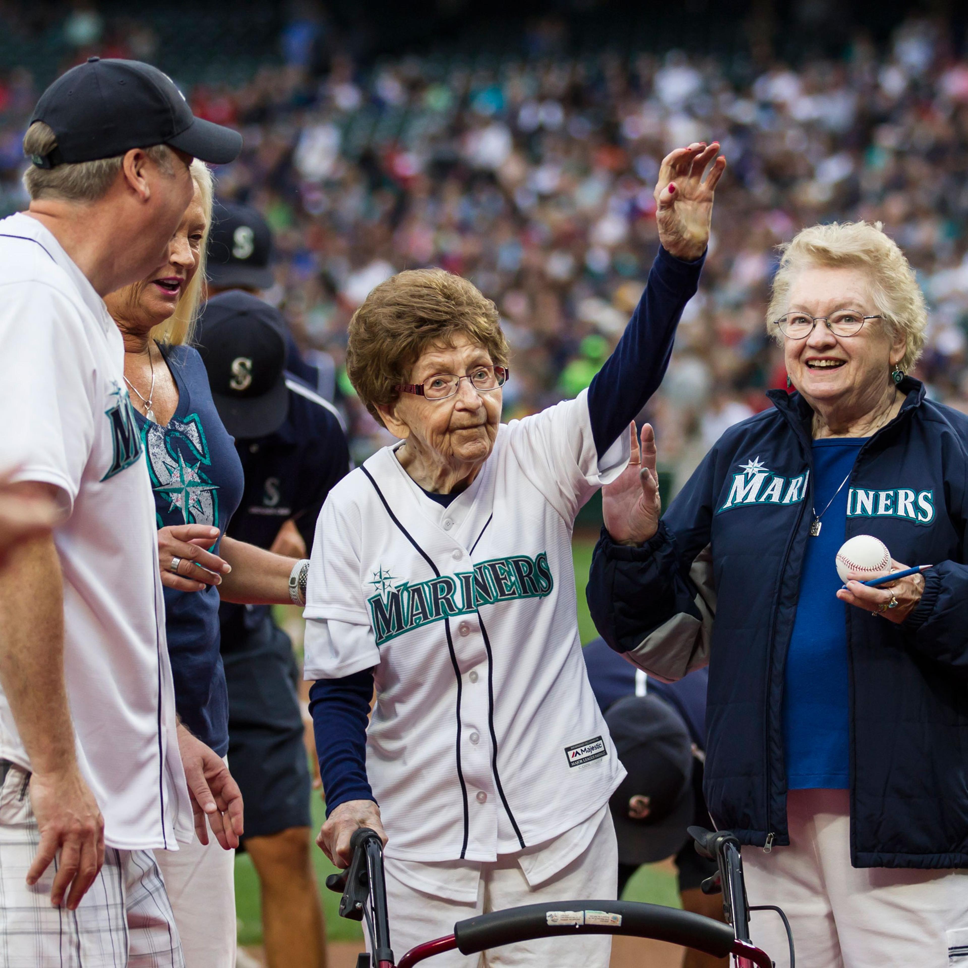 108-year-old Evelyn Jones, center, of Woodinville, Wash., waves to the crowd after throwing out the ceremonial first pitch on her birthday before a baseball game between the Seattle Mariners and the Los Angeles Angels, Saturday, July 11, 2015, in Seattle