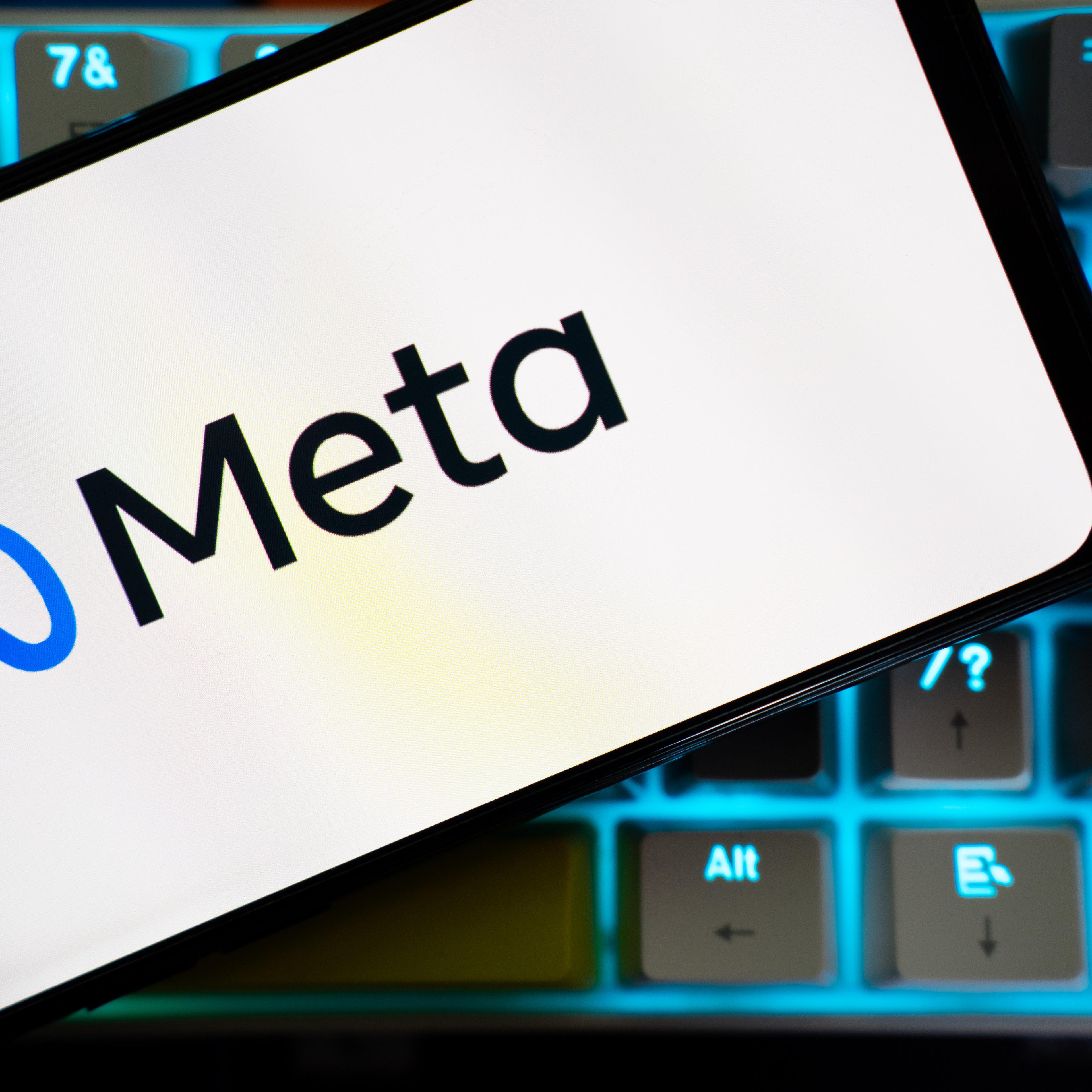 A mobile phone over a keyboard is seen, with the logo of Meta on its screen.