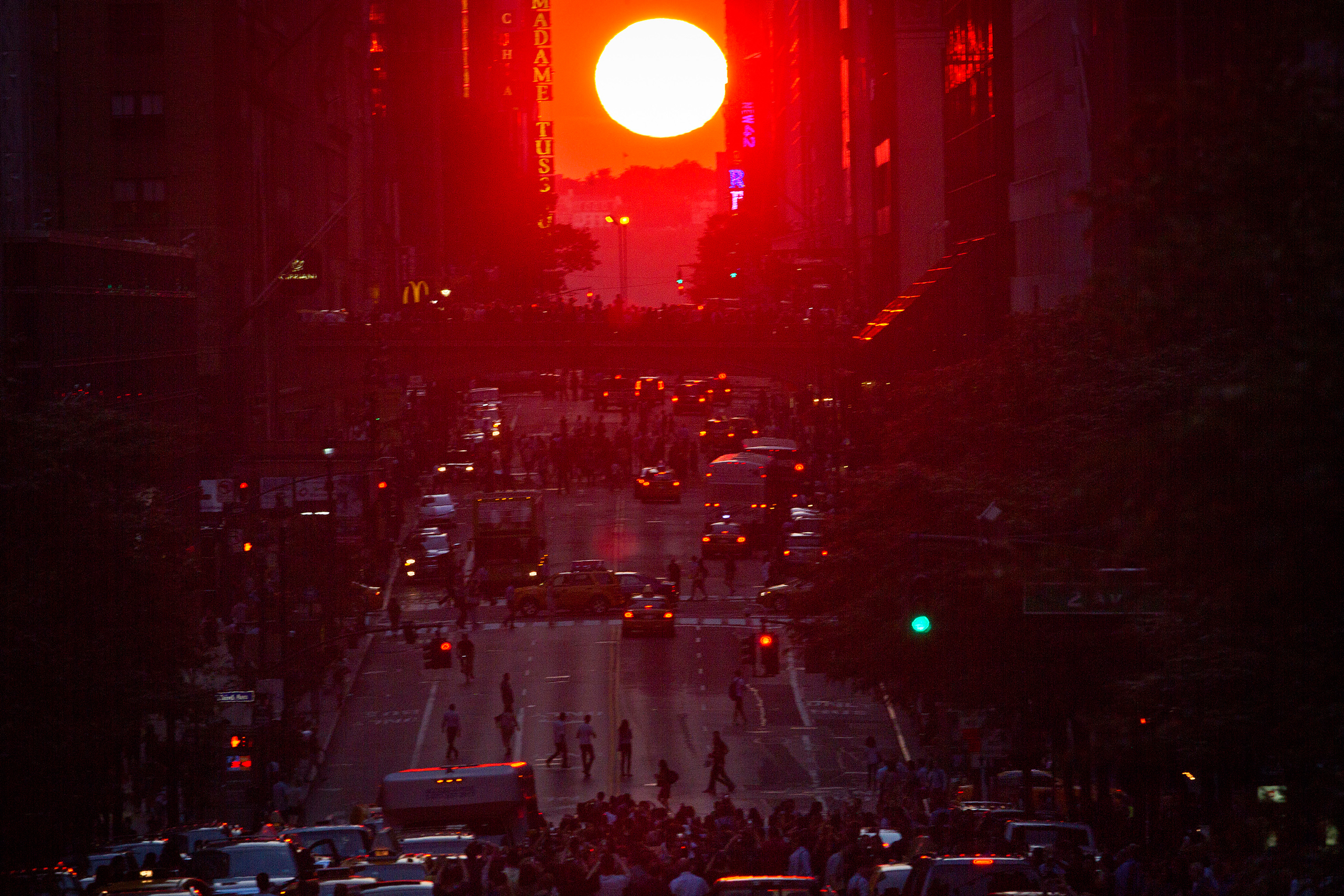 People crowd onto 42nd Street as they take photos of the "Manhattanhenge" phenomenon in the Manhattan borough of New York July 11, 2014. Manhattanhenge, coined by astrophysicist Neil deGrasse Tyson, occurs twice a year, when the setting sun aligns itself