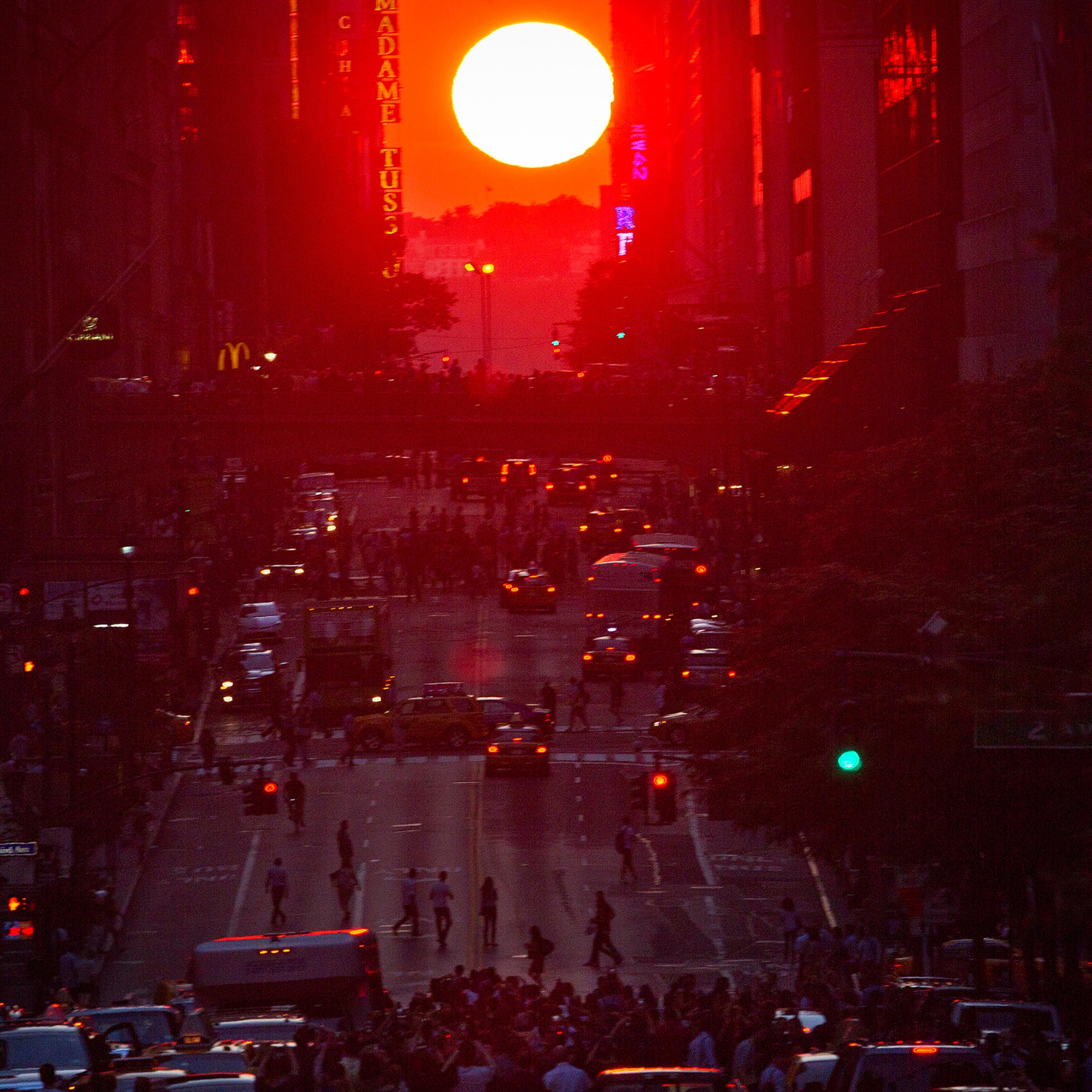 People crowd onto 42nd Street as they take photos of the "Manhattanhenge" phenomenon in the Manhattan borough of New York July 11, 2014. Manhattanhenge, coined by astrophysicist Neil deGrasse Tyson, occurs twice a year, when the setting sun aligns itself