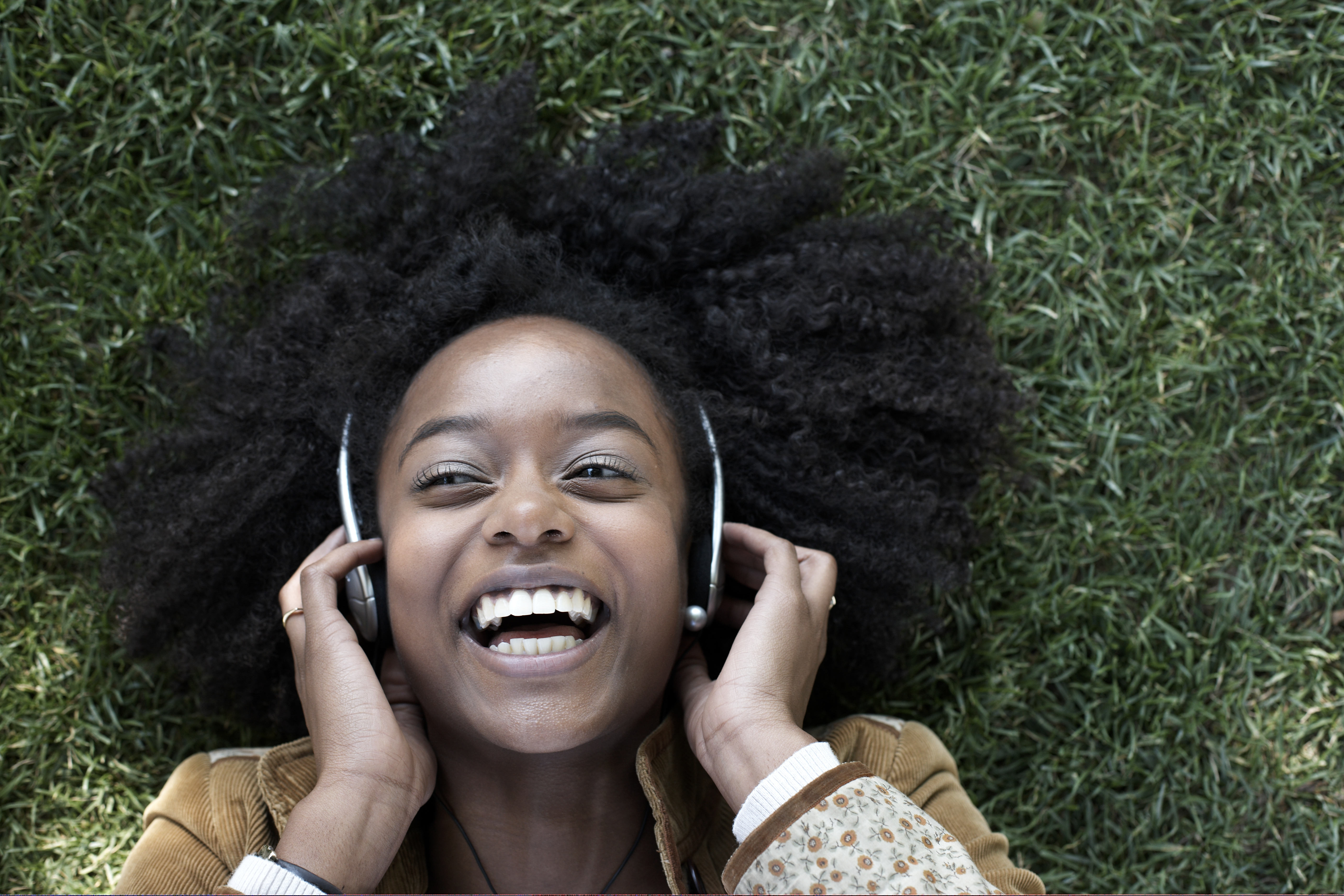 Woman listening to music lying on grass