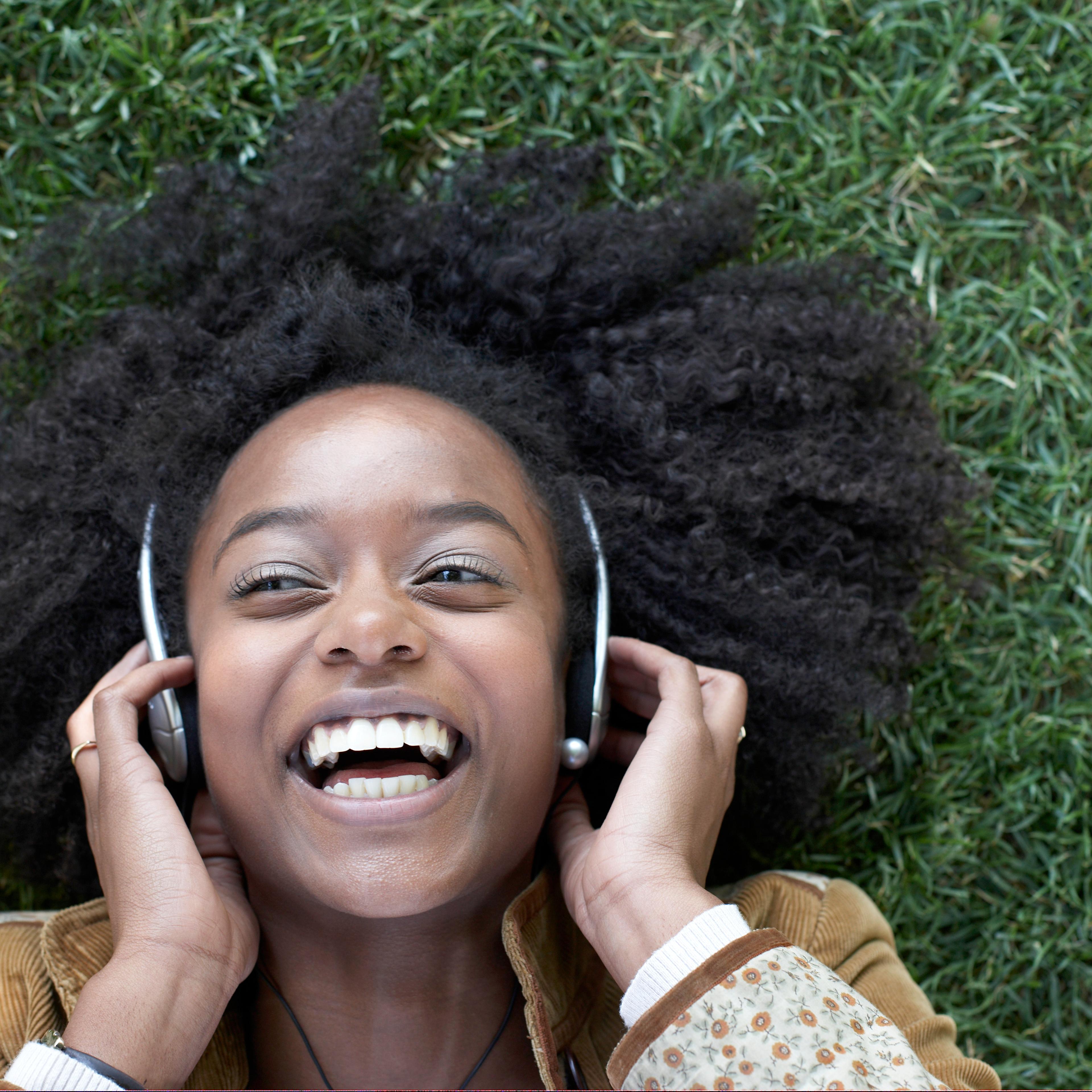 Woman listening to music lying on grass