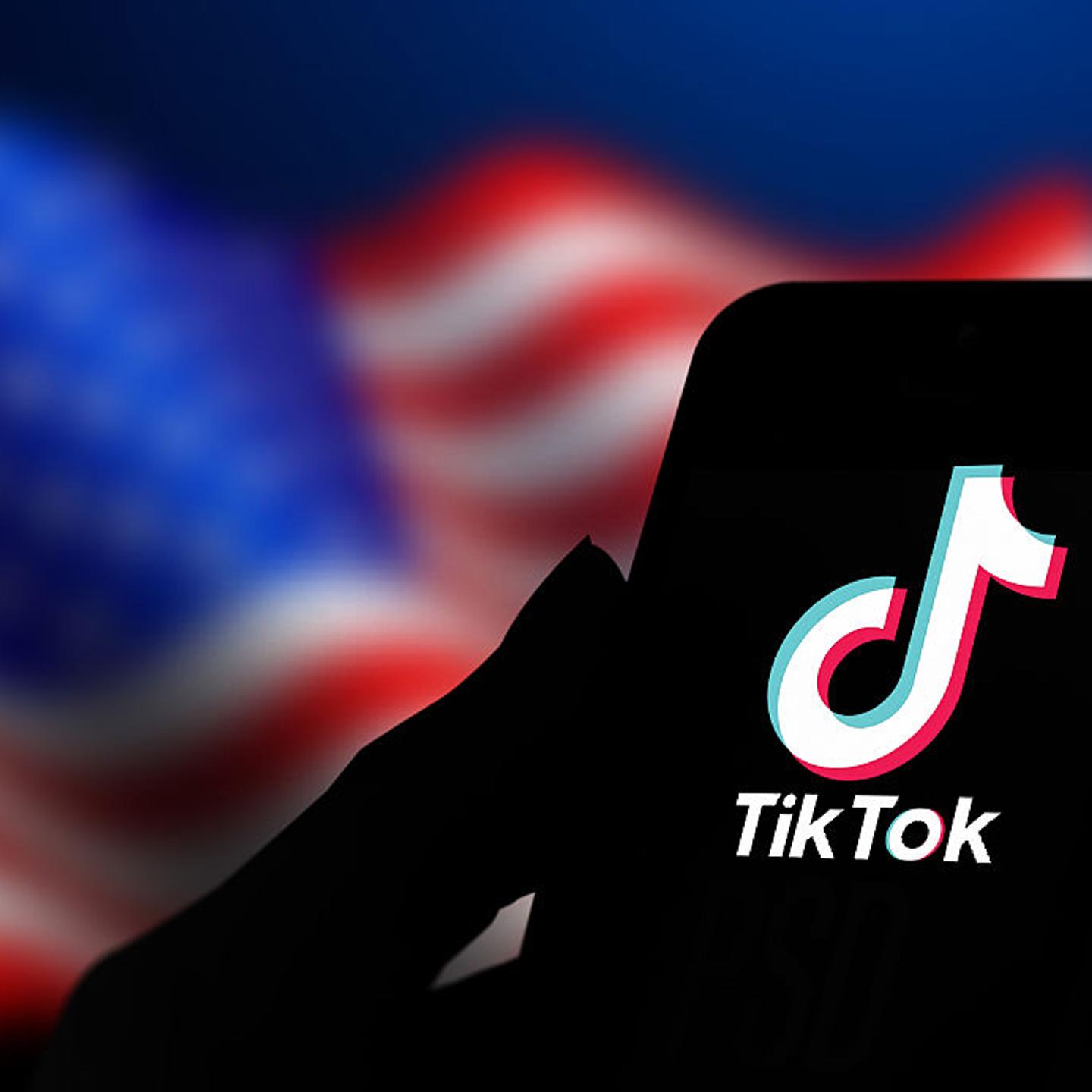 TikTok logo displayed on phone in front of backdrop of U.S. flag