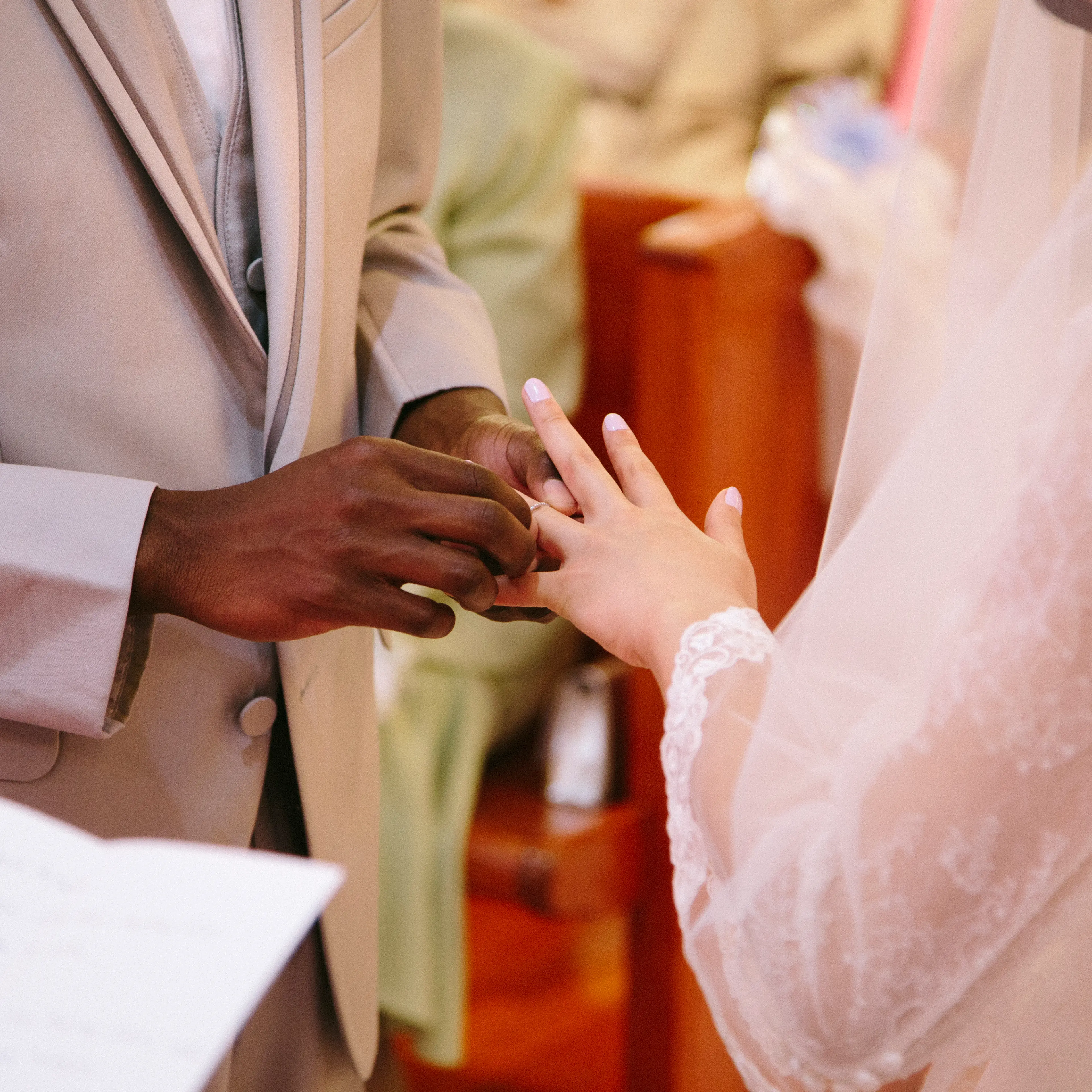 Cropped view of bridegroom putting ring on brides finger at wedding ceremony