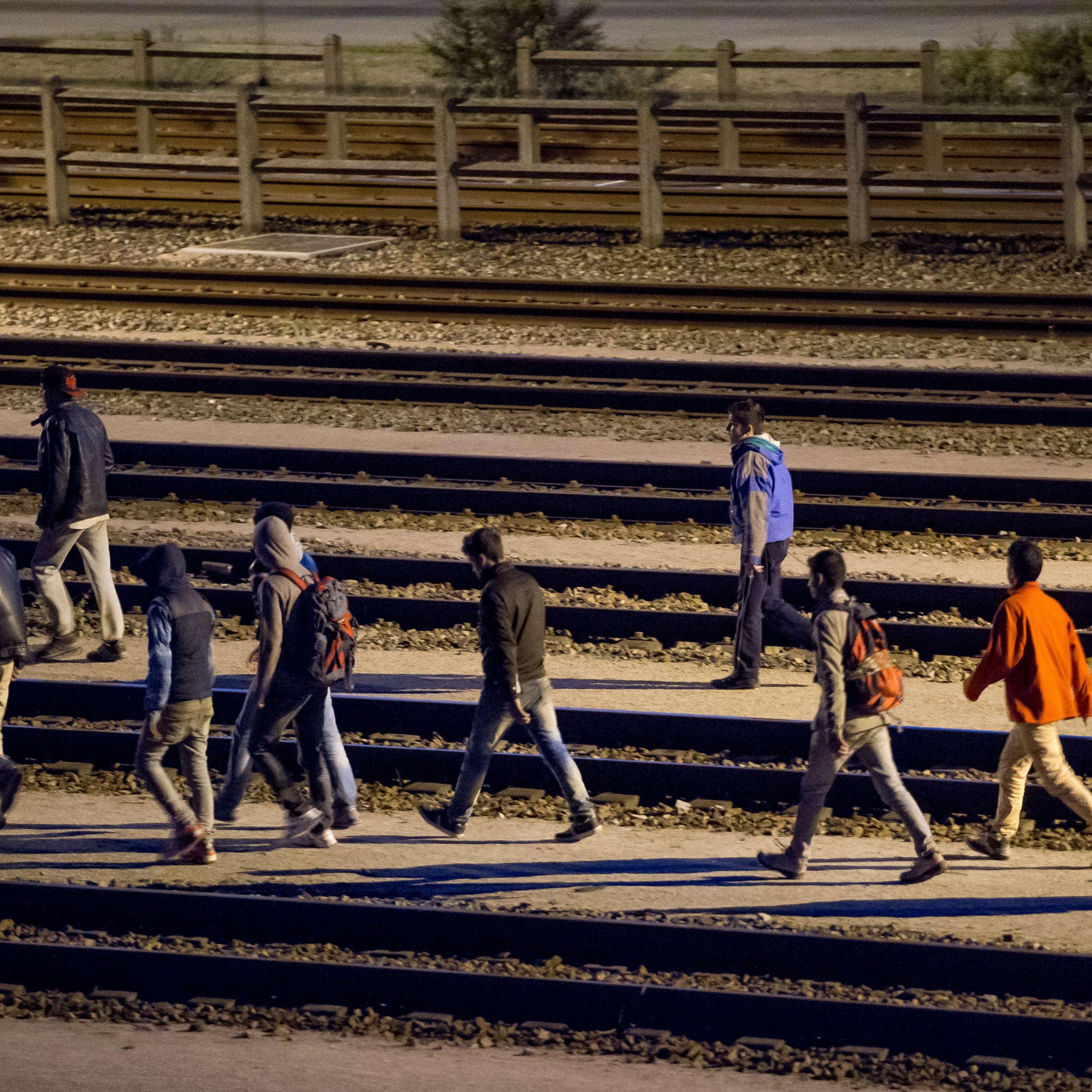 Migrants walk along railway tracks at the Eurotunnel terminal on July 28, 2015 in Calais-Frethun.