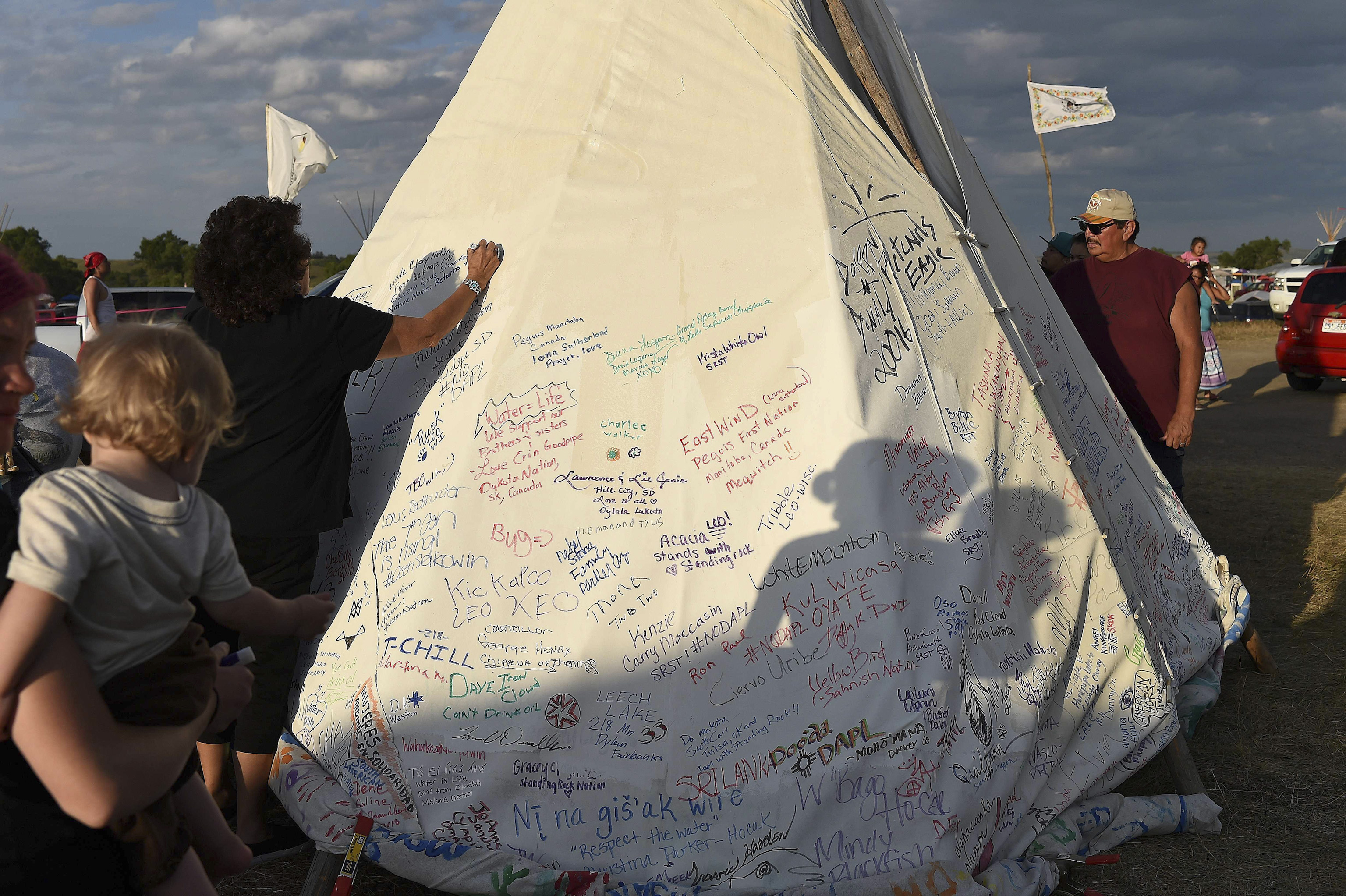 People sign a teepee with words of support for protestors at an encampment where hundreds of people have gathered to join the Standing Rock Sioux Tribe's protest against the construction of the Dakota Access Pipe (DAPL), near Cannon Ball, North Dakota, o