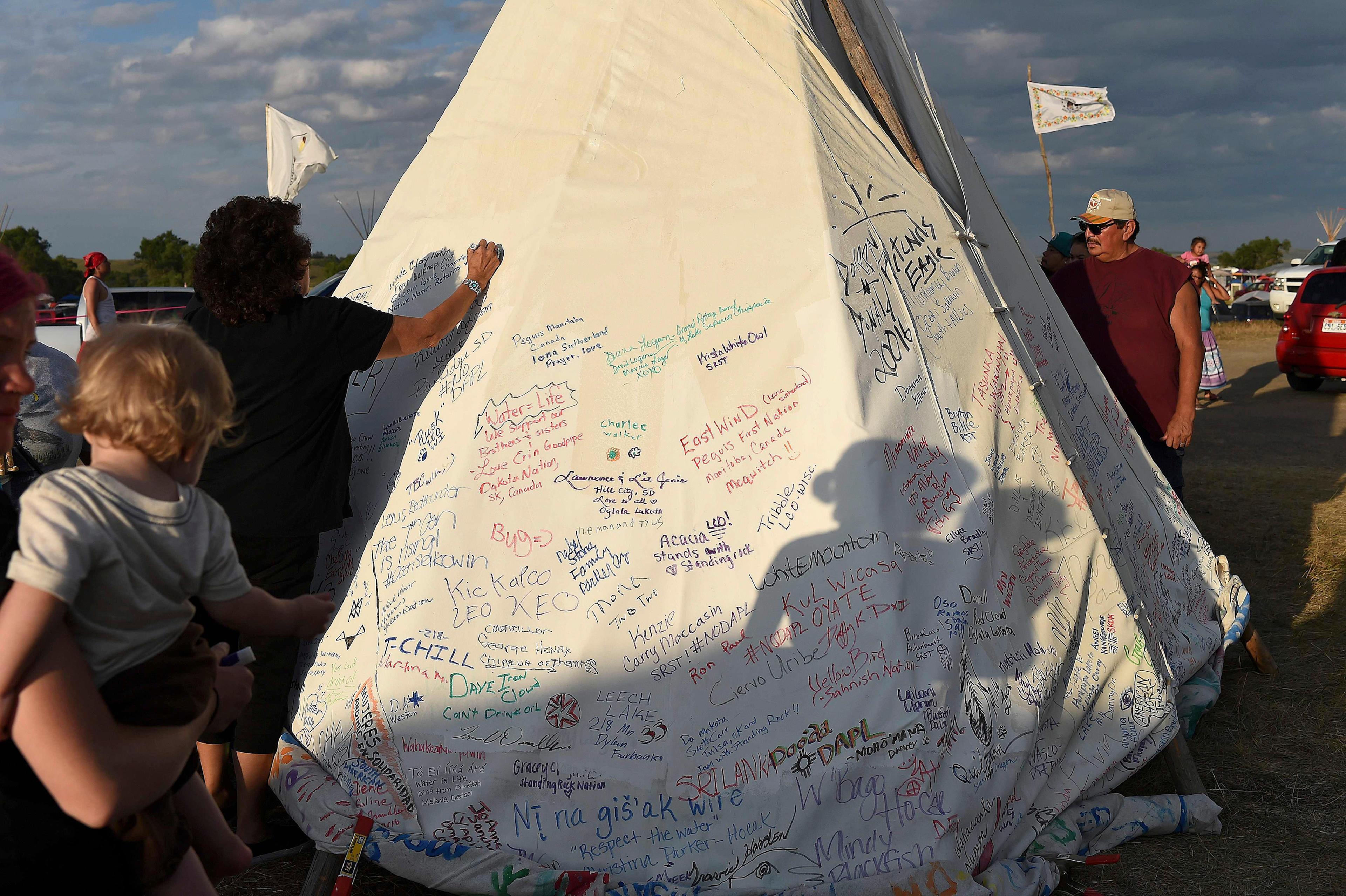 People sign a teepee with words of support for protestors at an encampment where hundreds of people have gathered to join the Standing Rock Sioux Tribe's protest against the construction of the Dakota Access Pipe (DAPL), near Cannon Ball, North Dakota, o
