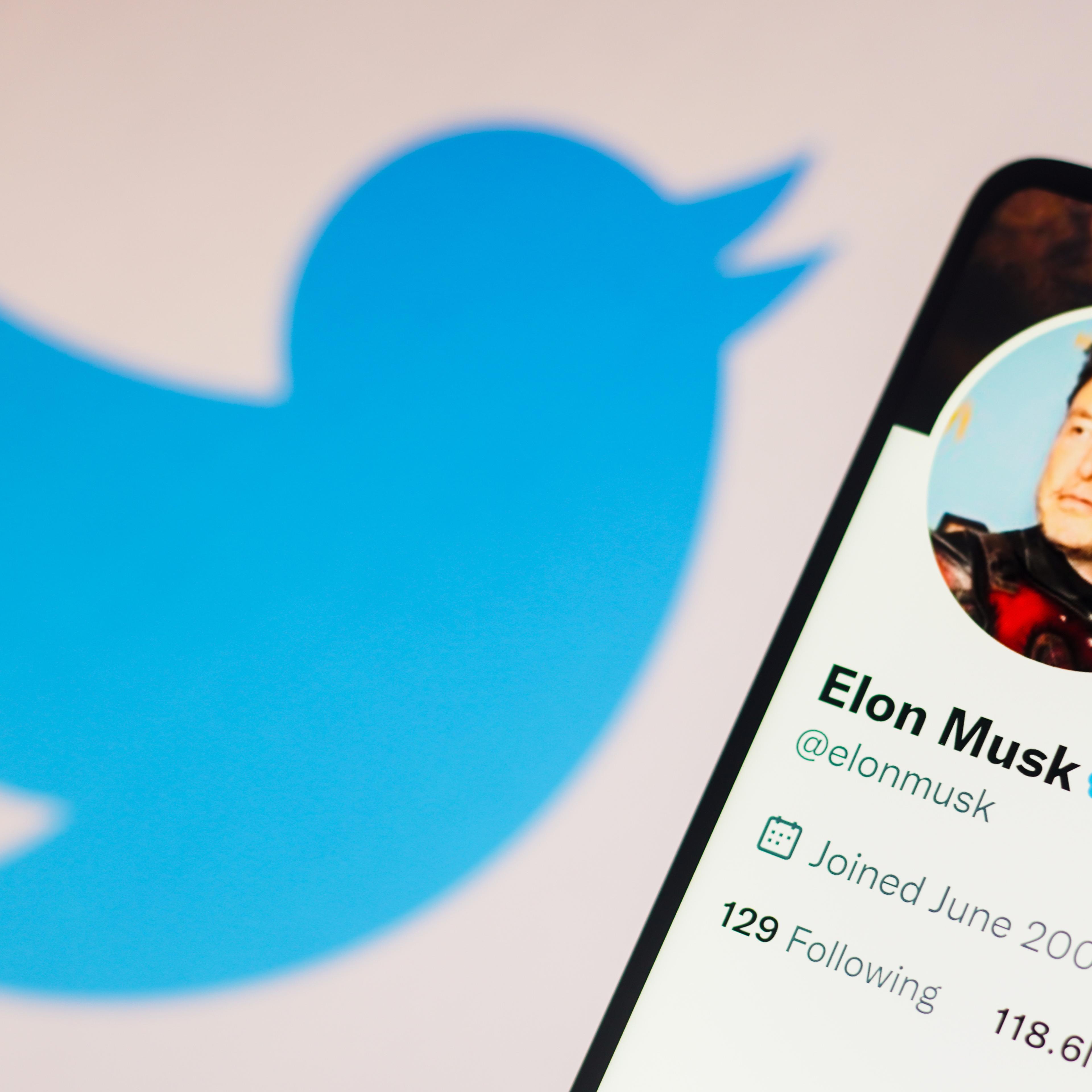 In this photo illustration, Elon Musk's Twitter account is displayed on a smartphone with the Twitter logo in the background.