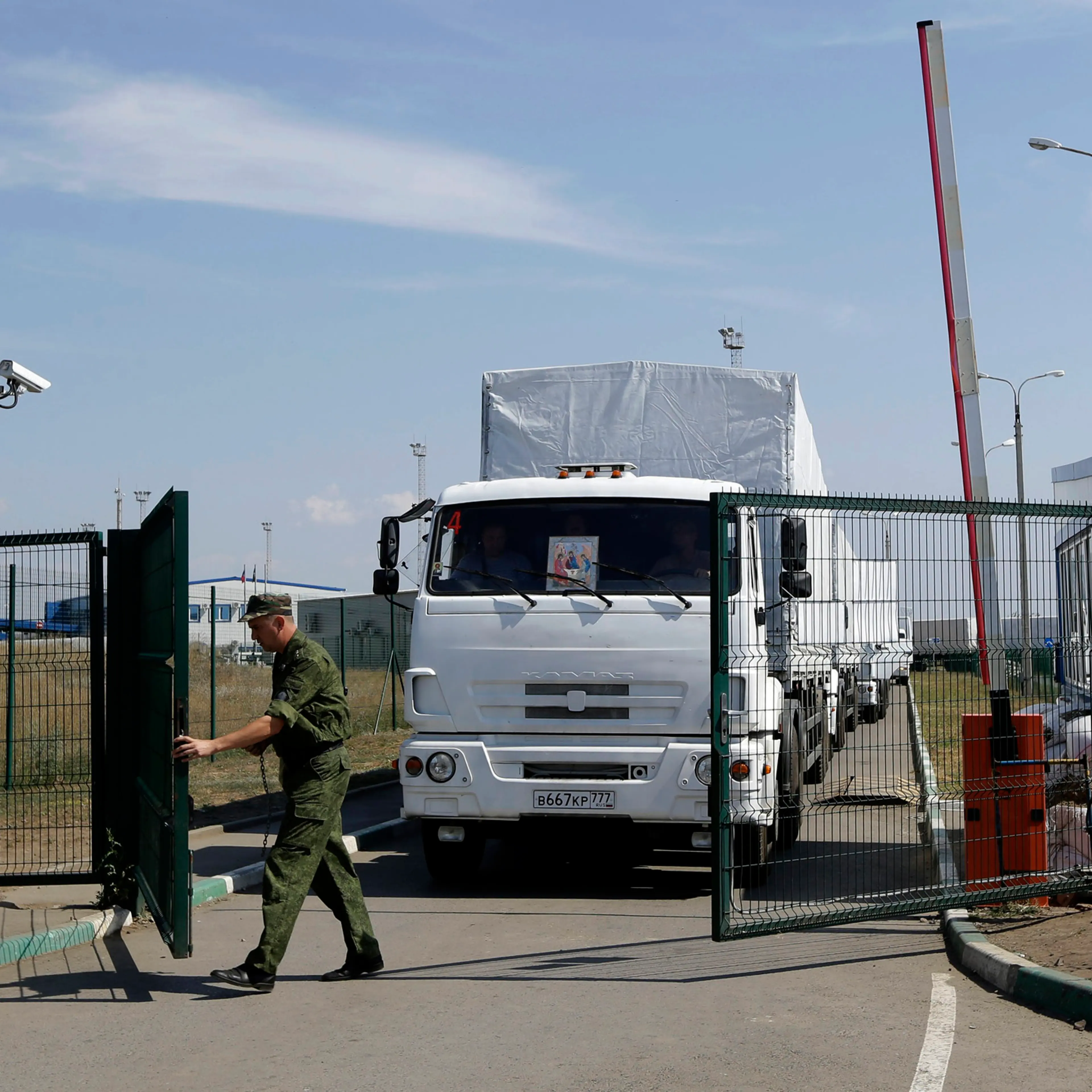 A Russian border guard opens a gate into the Ukraine for the first trucks heading into the country from the Russian town of Donetsk, Rostov-on-Don region, Russia, Aug. 22, 2014.