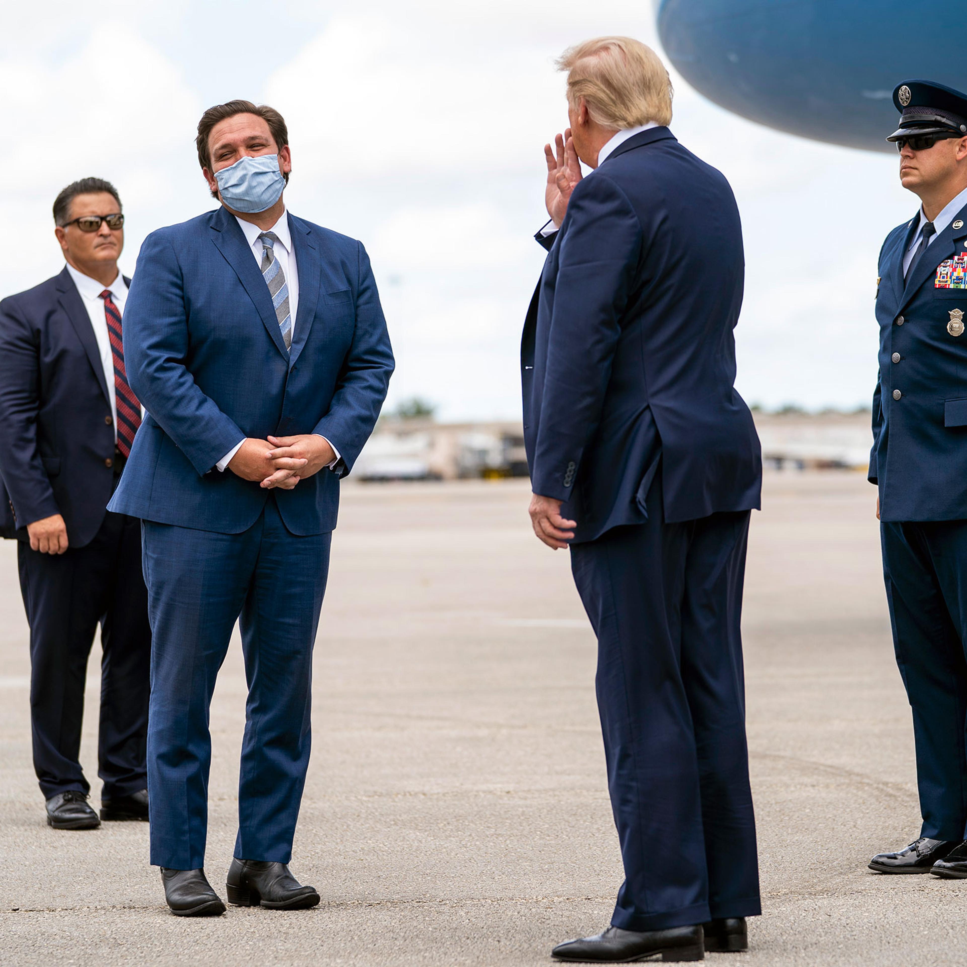 President Donald Trump is greeted by Gov. Ron DeSantis of Florida upon his arrival at Palm Beach International Airport
