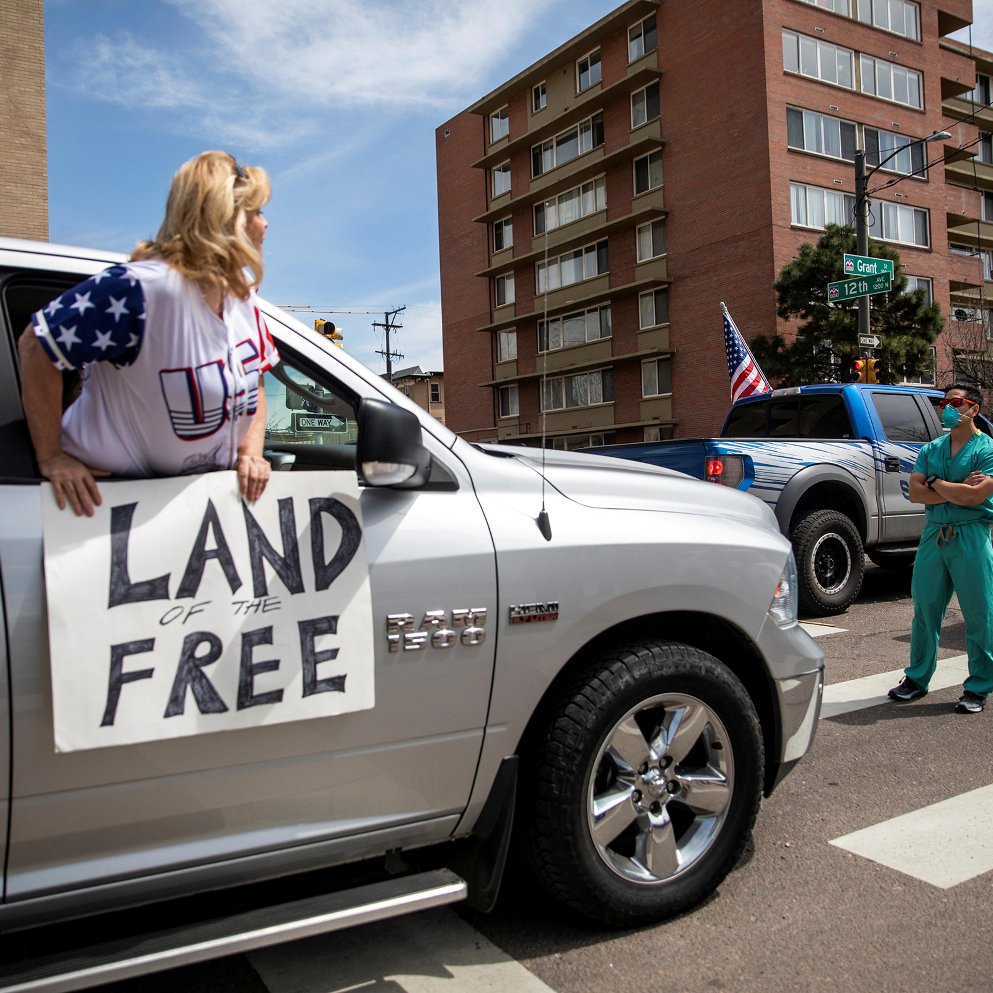 Health care workers stand in the street as a counter-protest to those demanding the stay-at-home order be lifted in Denver