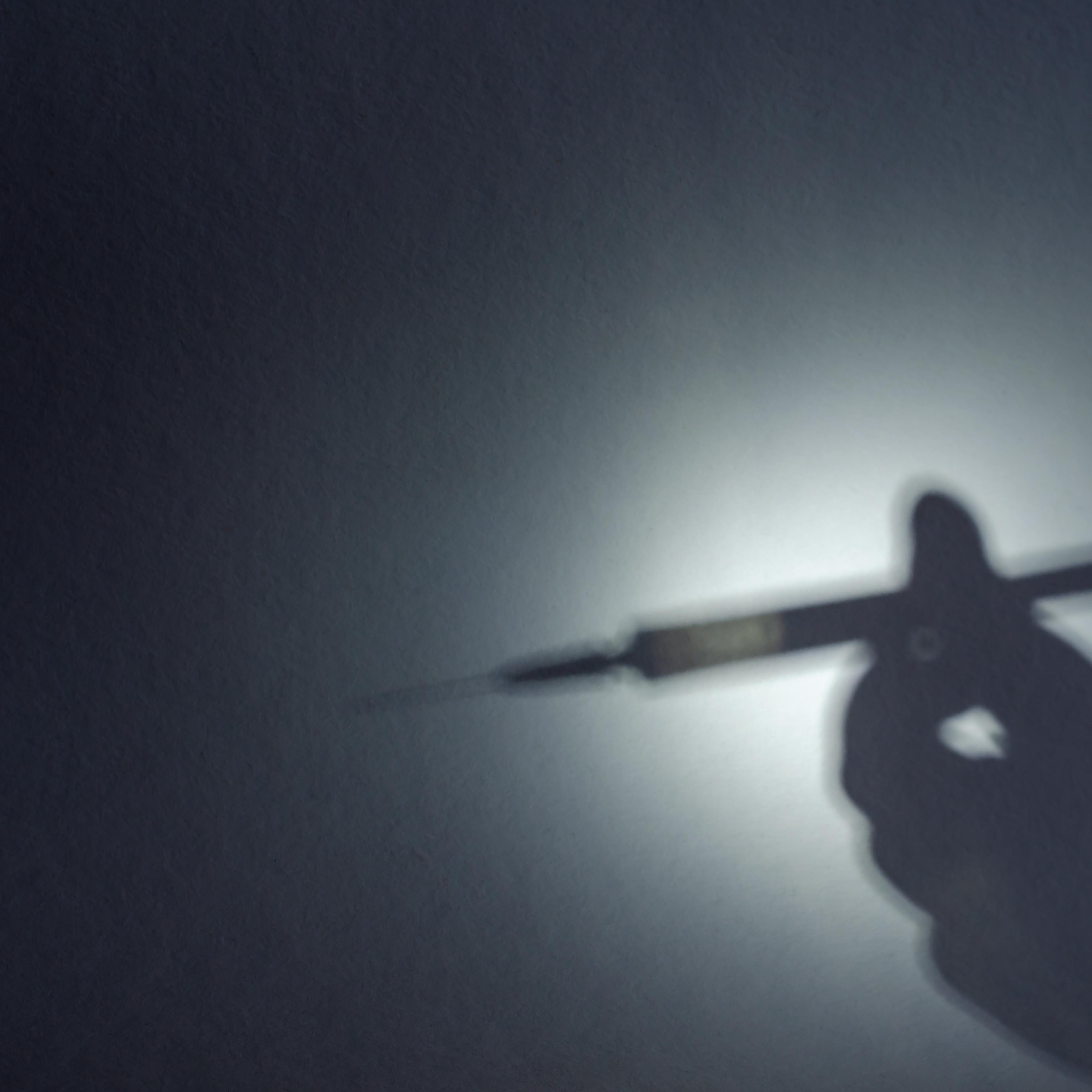 The shadow of a hand with a syringe on a dark textured backgroun