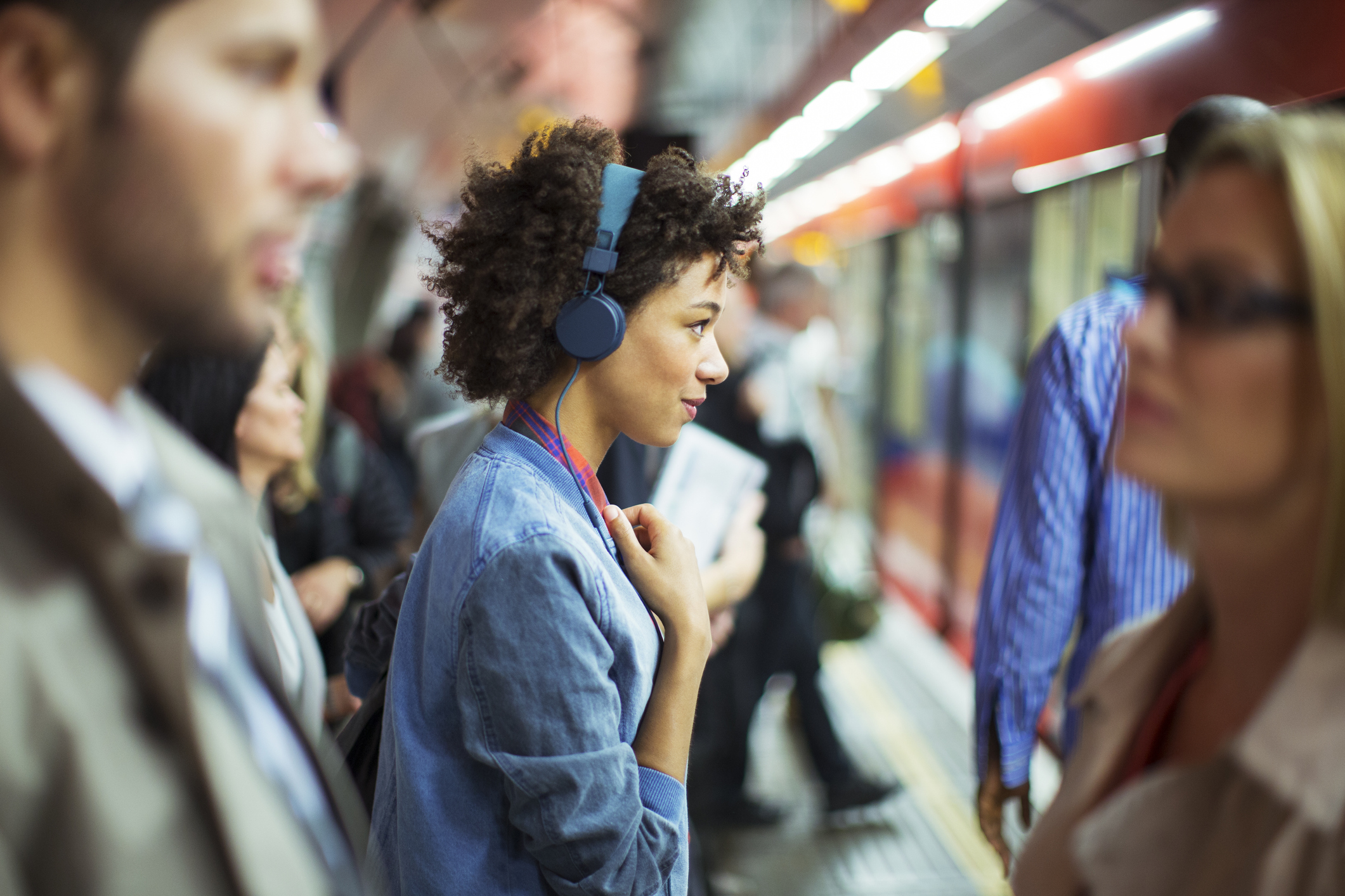 Woman listening to headphones in train station